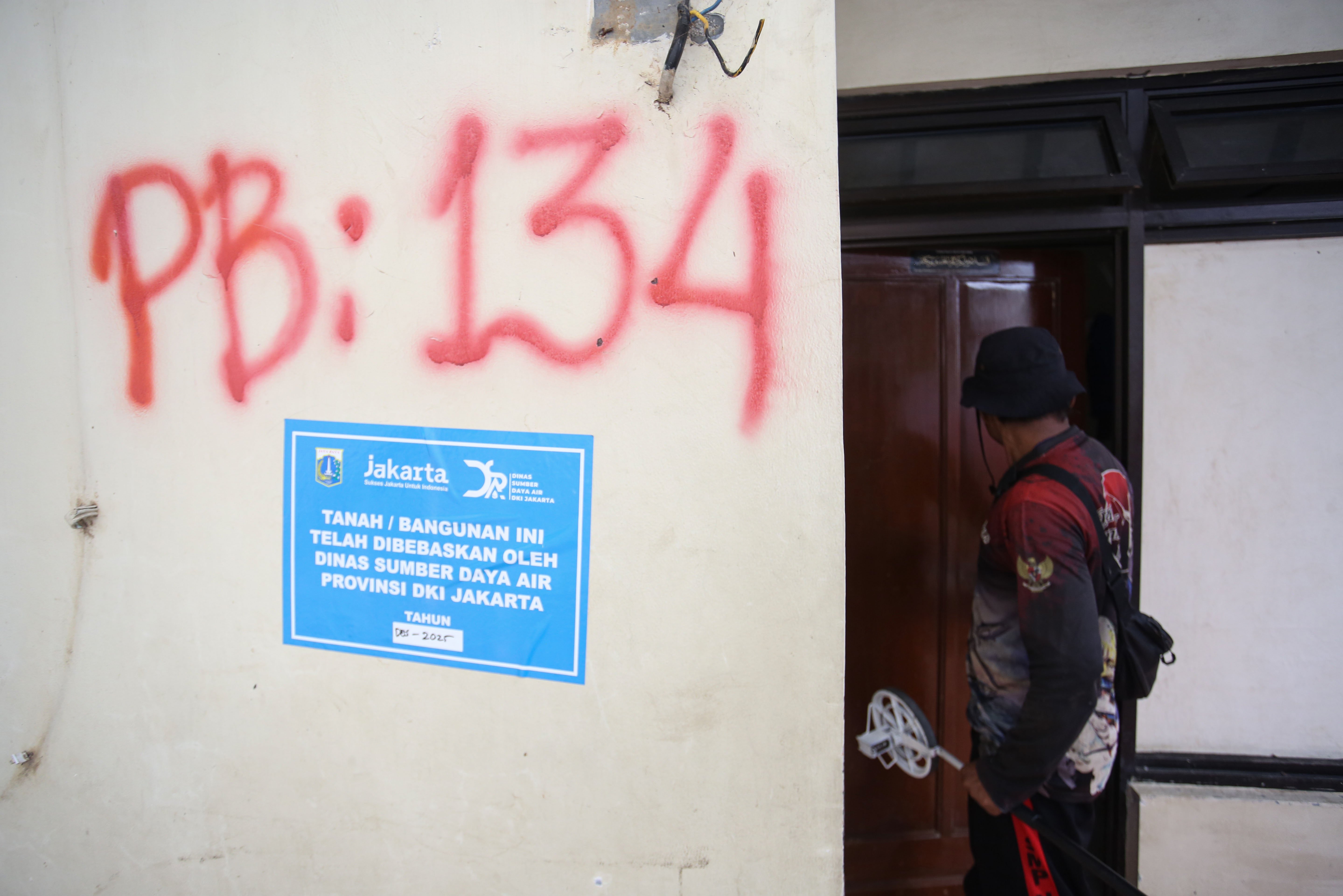 Warga mengecek rumahnya yang akan dibongkar di bantaran Kali Ciliwung, Taman Harapan, Cawang, Jakarta Timur, Jumat (6/2/2026). Pemprov DKI Jakarta membebaskan lahan dengan membongkar rumah warga untuk proyek normalisasi Kali Ciliwung sebagai langkah untuk mengatasi banjir yang kerap terjadi di wilayah tersebut.