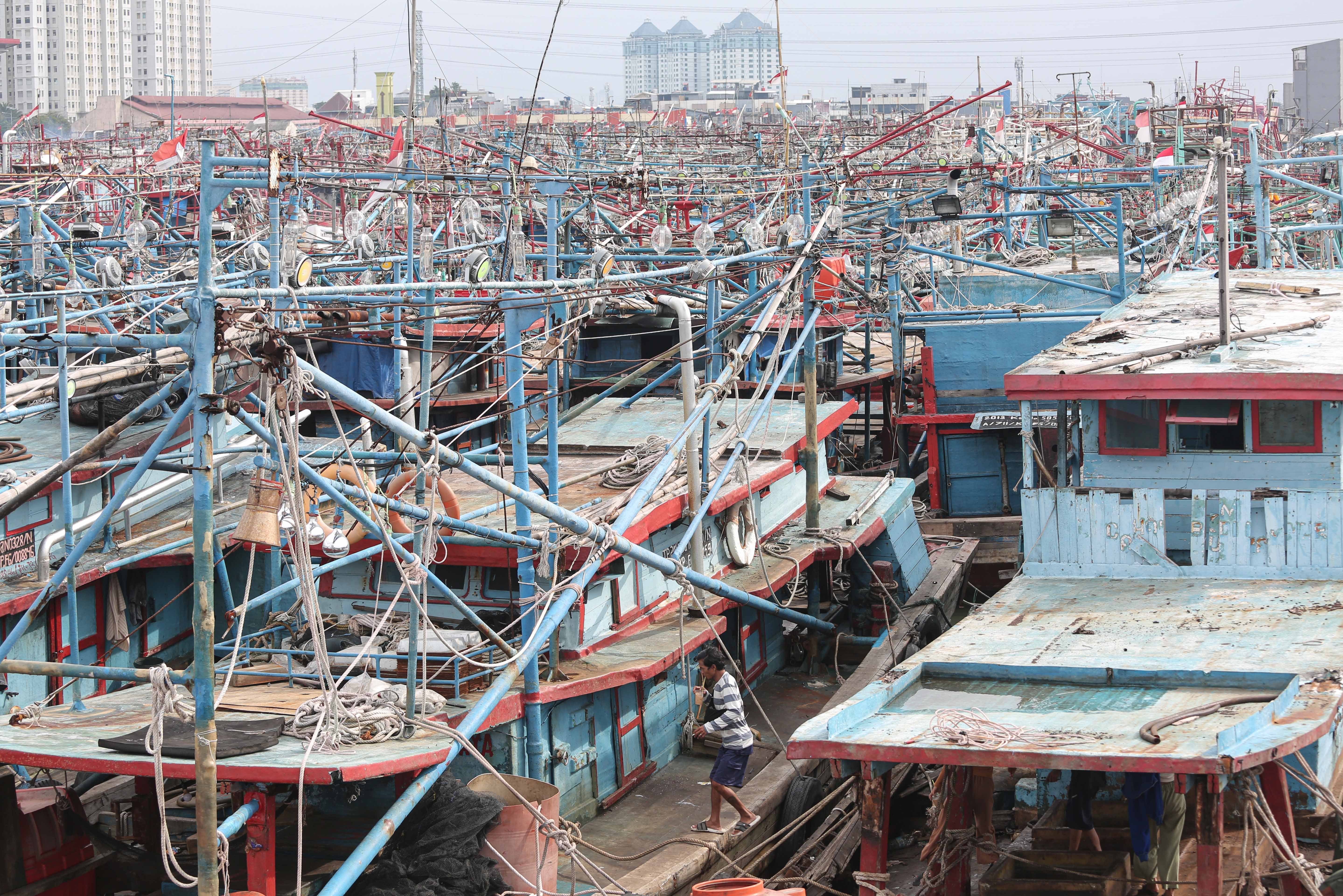 Warga berjalan di atas kapal kapal nelayan yang menumpuk saat bersandar di Pelabuhan Perikanan Nusantara (PPN) Muara Angke, Jakarta Utara, Senin (9/2/2026). Kadatan kapal tersebut terjadi karena kondisi cuaca buruk yang membuat kapal tidak melaut hingga menumpuk dan melebihi kapasitas kolam. 