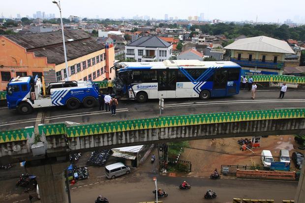 Sejumlah petugas berada di dekat bus TransJakarta yang mengalami kecelakaan tabrakan antar sesama bus TransJakarta di jalur layang atau jalur langit Koridor 13, Cipulir, Jakarta, Senin (23/2/2026). Tabrakan tersebut diduga karena kedua sopir mengantuk dan sebanyak 18 penumpang mengalami luka ringan dalam peristiwa itu.