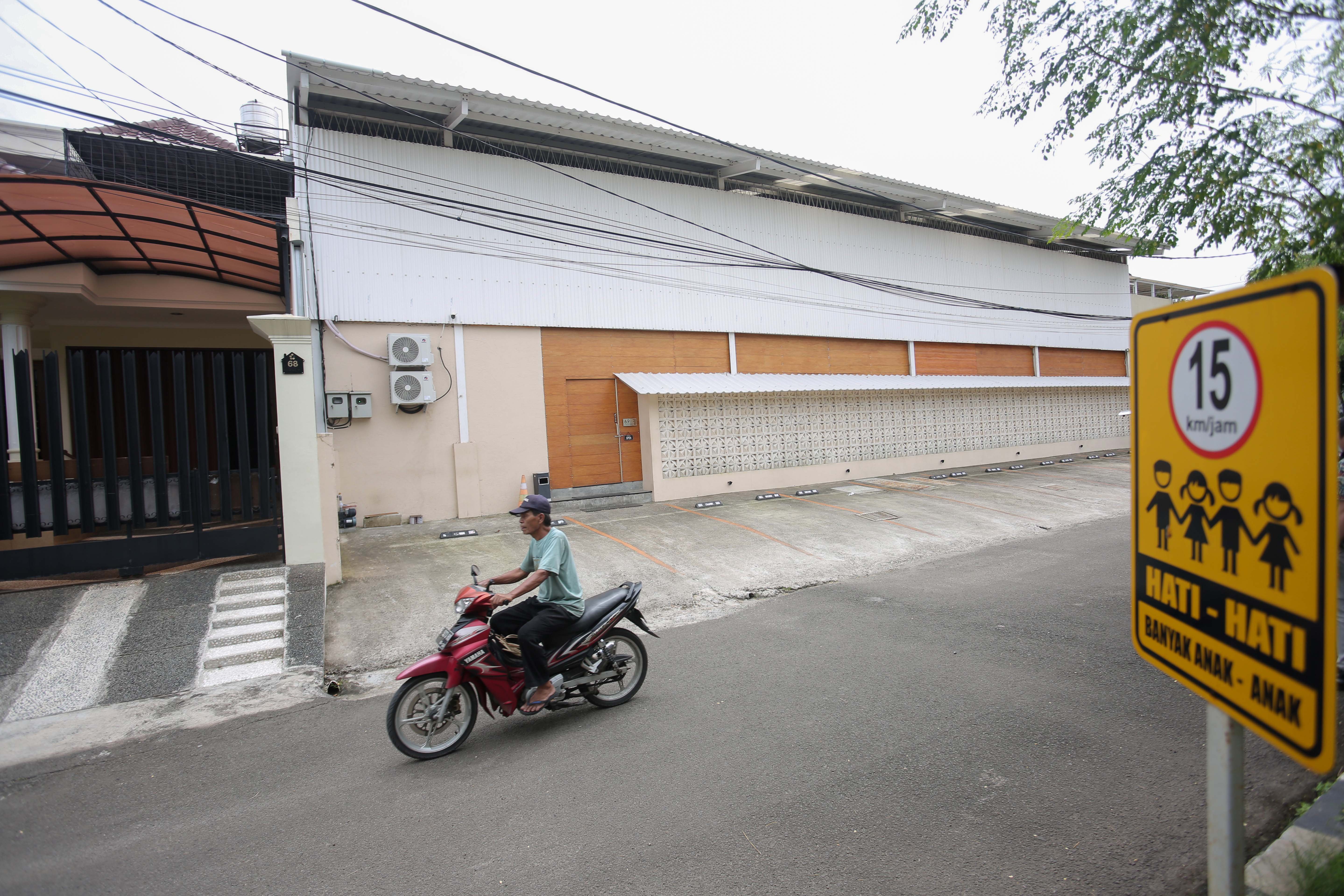 Pengendara sepeda motor melintas di dekat rumah warga (kiri) dan lapangan padel (kanan) di kawasan perumahan, Jalan Pulomas Barat II, Kayu Putih, Pulogadung, Jakarta Timur, Kamis (26/2/2026). Berdasarkan penuturan warga aktivitas olahraga di lapangan padel tersebut kerap menimbulkan suara bising dan mengganggu ketenangan warga.
