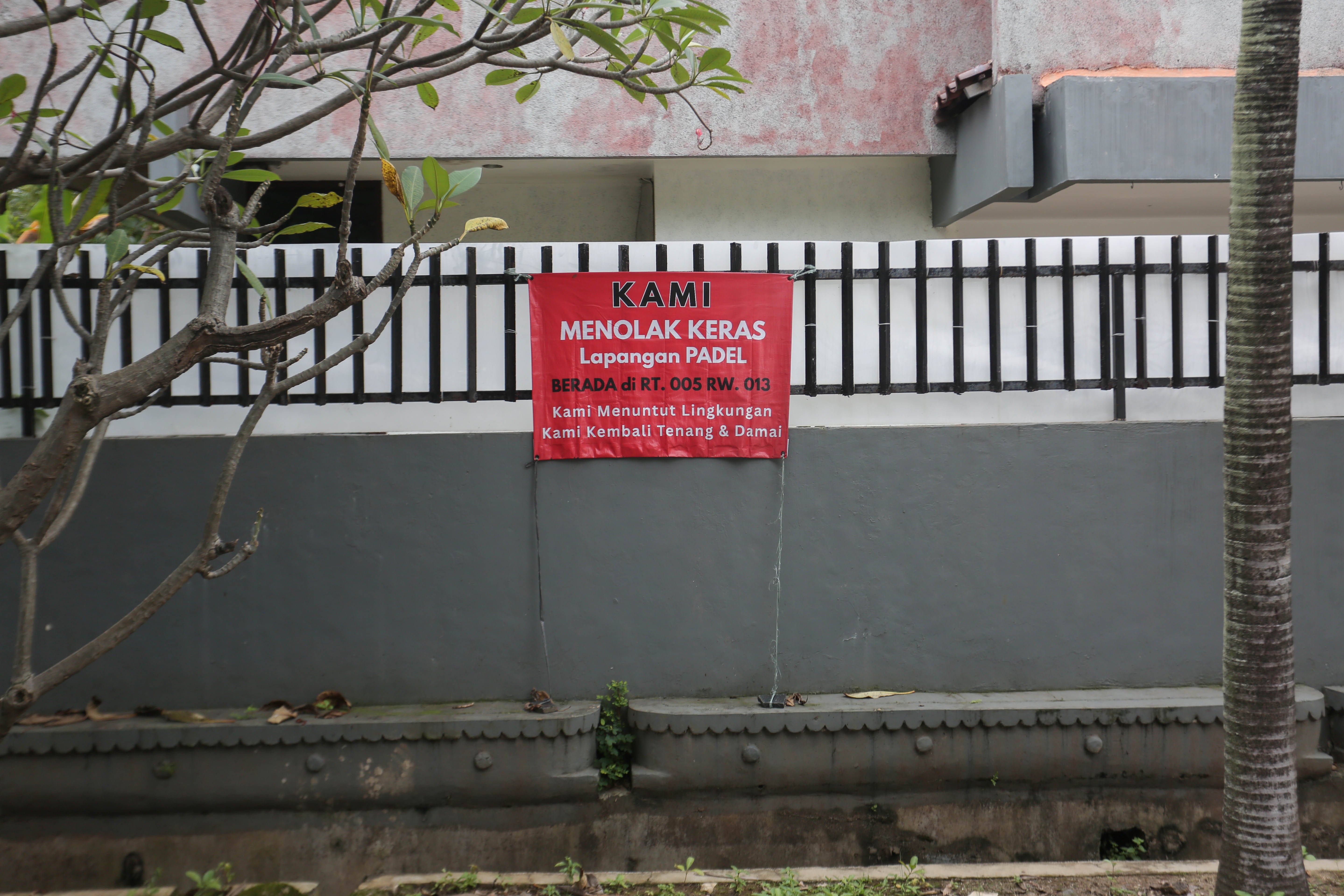 Spanduk penolakan lapangan padel di kawasan perumahan, Jalan Pulomas Barat II, Kayu Putih, Pulogadung, Jakarta Timur, Kamis (26/2/2026). Berdasarkan penuturan warga aksi pemasangan spanduk tersebut sebagai bentuk protes terhadap aktivitas olahraga di lapangan padel yang kerap menimbulkan suara bising dan mengganggu ketenangan warga.