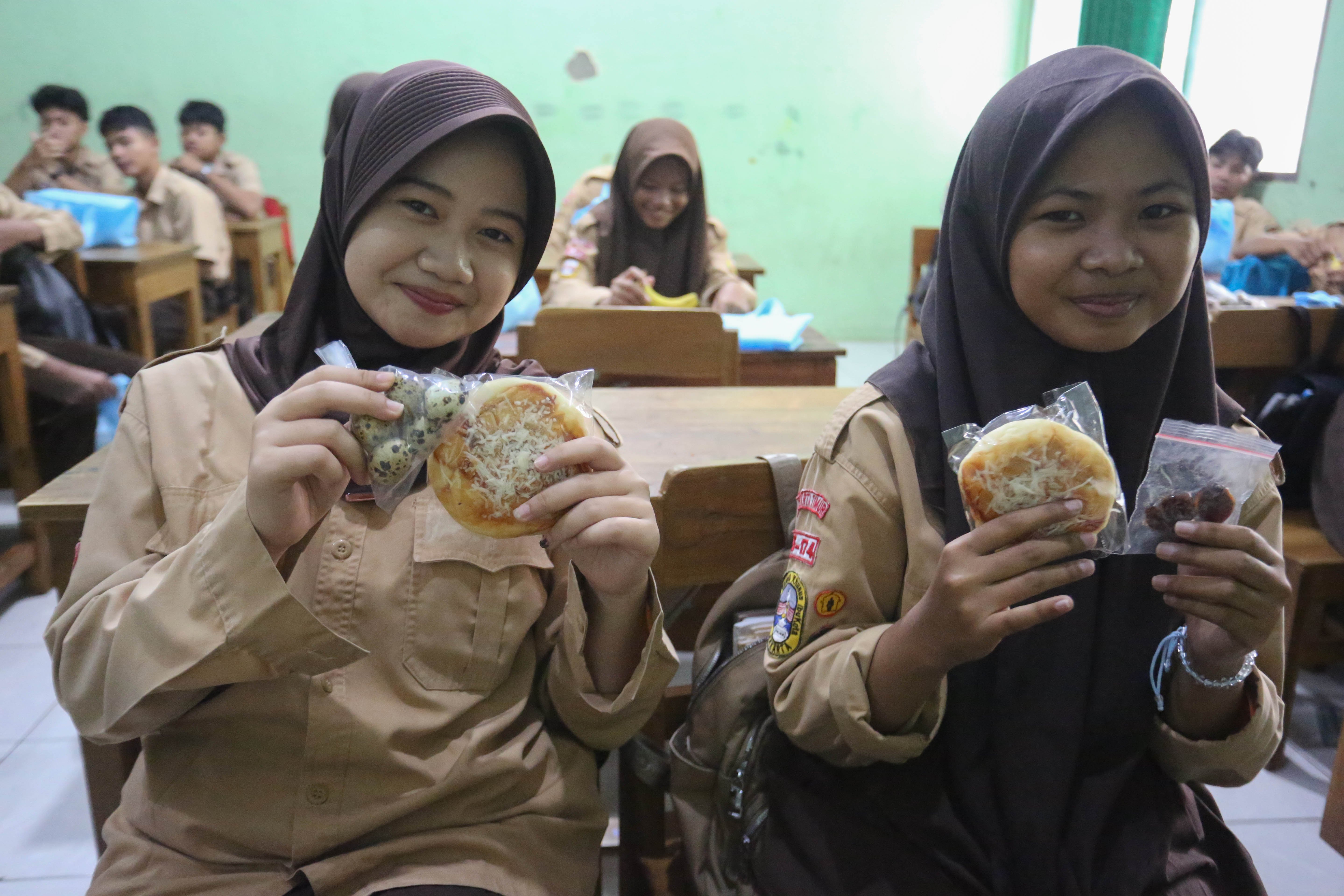 Siswi menunjukkan makanan pada paket Makan Bergizi Gratis (MBG) yang dibagikan di MTs As-Syafi\'iyah 04 Jakarta, Rabu (4/3/2026). Pada bulan Ramadan siswa mendapatkan MBG untuk dimakan di rumah saat berbuka puasa dengan menu yang terdiri dari roti, buah pisang, kurma dan telur puyuh rebus.