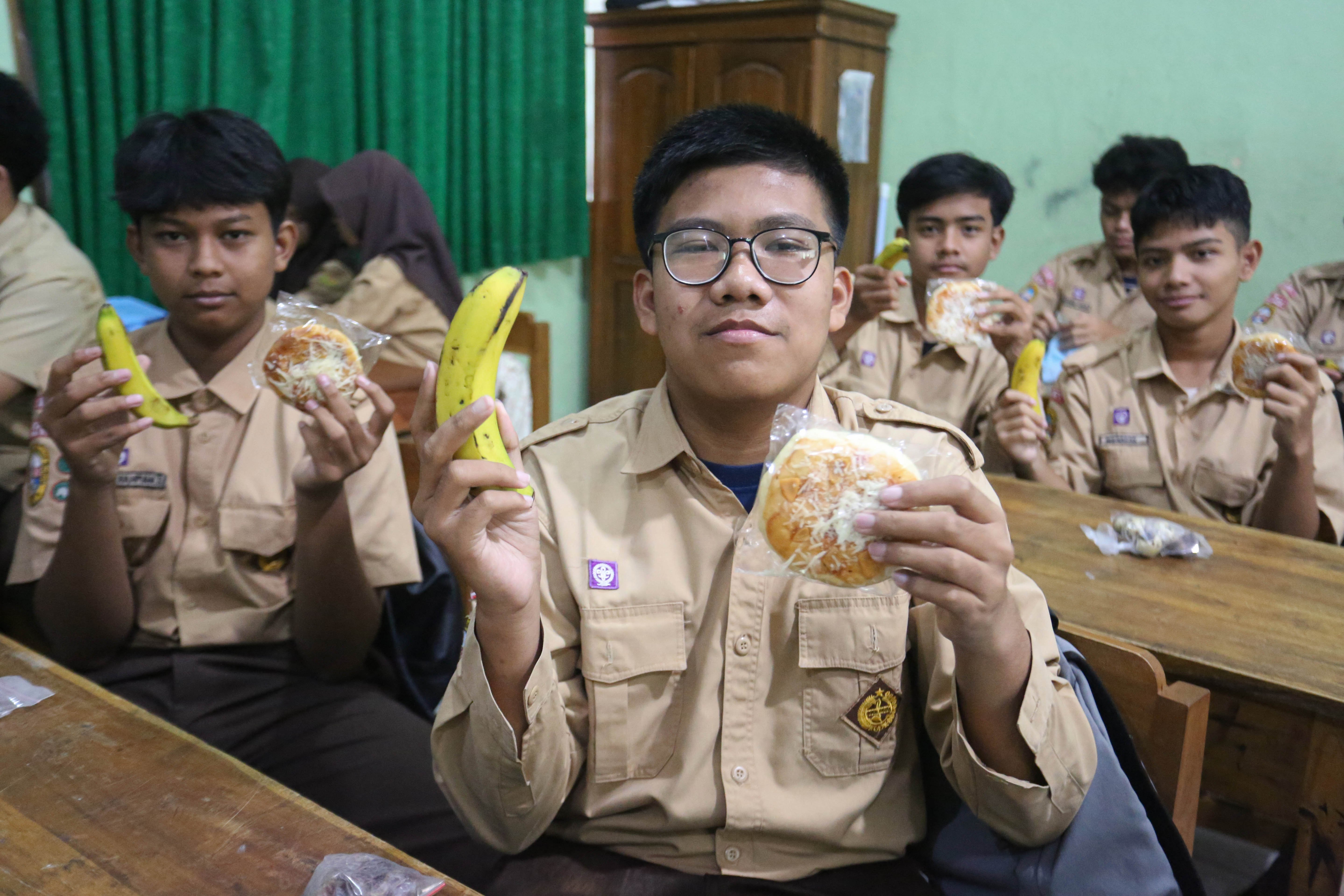 Siswa menunjukkan makanan pada paket Makan Bergizi Gratis (MBG) yang dibagikan di MTs As-Syafi\'iyah 04 Jakarta, Rabu (4/3/2026). Pada bulan Ramadan siswa mendapatkan MBG untuk dimakan di rumah saat berbuka puasa dengan menu yang terdiri dari roti, buah pisang, kurma dan telur puyuh rebus.