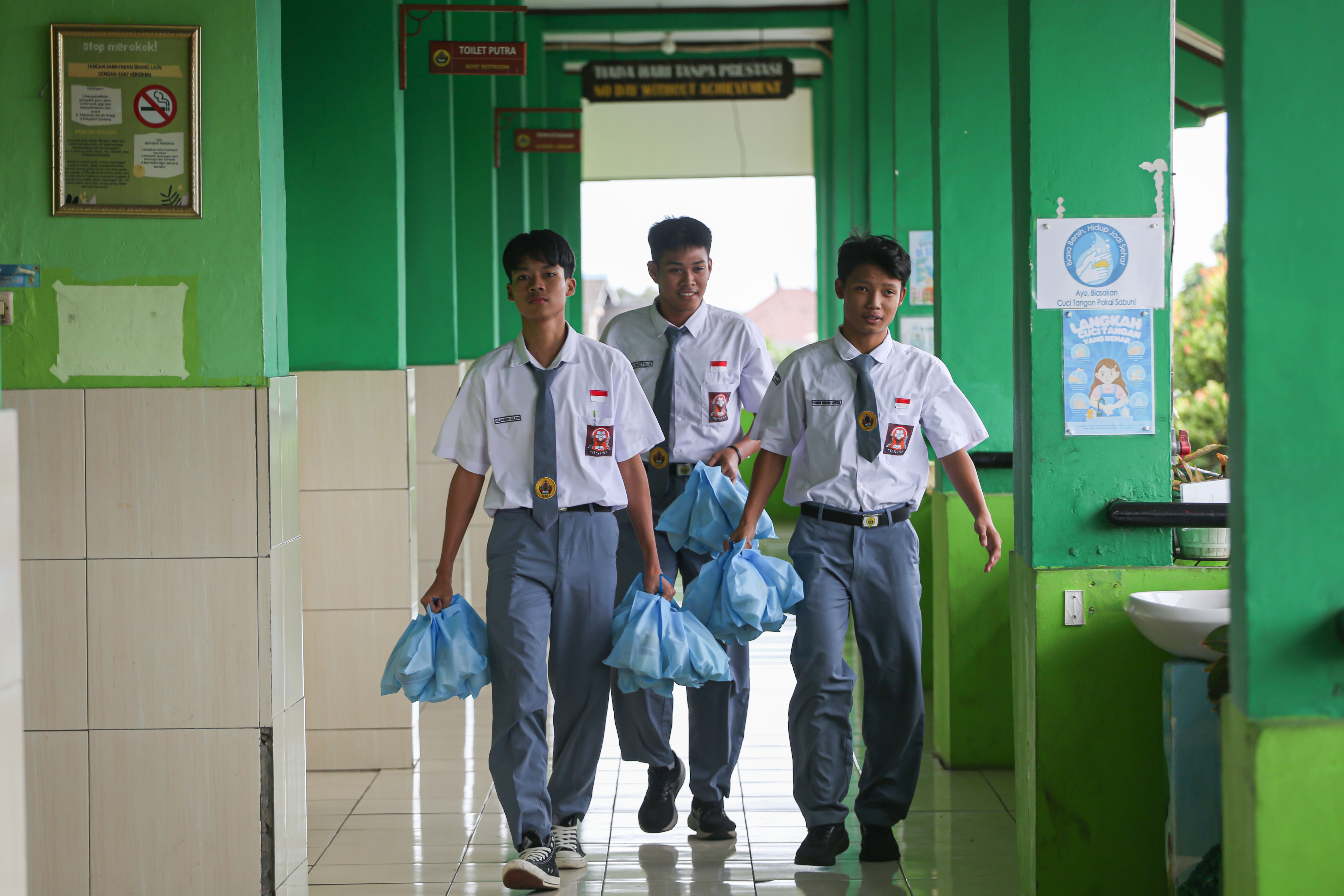 Siswa membawa paket Makan Bergizi Gratis (MBG) yang akan dibangikan di SMA Negeri 64 Jakarta, Selasa (3/3/2026). Pada bulan Ramadan siswa mendapatkan MBG untuk dimakan di rumah saat berbuka puasa dengan menu yang terdiri dari dimsum ayam wortel, puding susu stroberi dan buah jeruk.