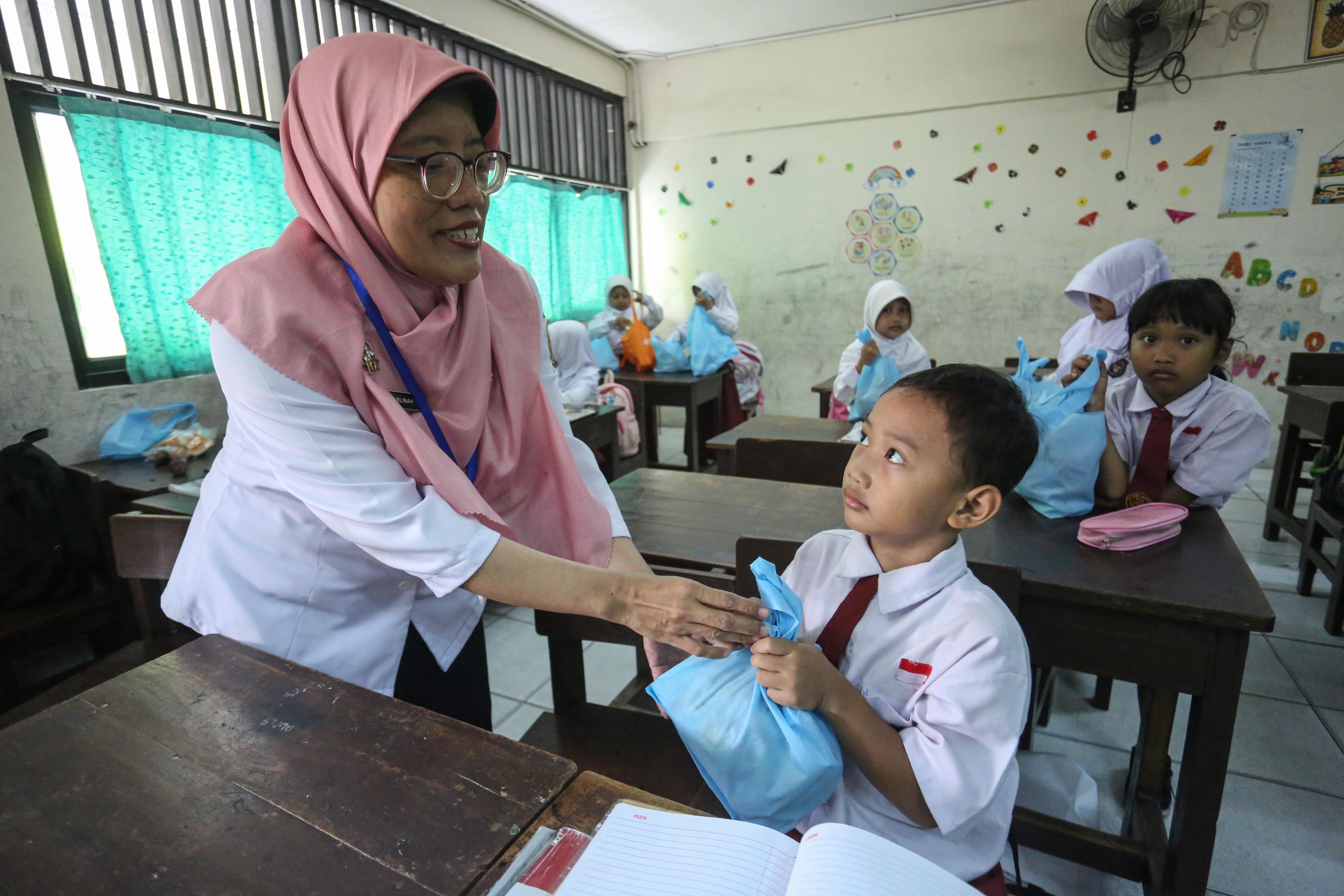 Guru membagikan paket Makan Bergizi Gratis (MBG) kepada siswa di SDN Slipi 15, Jakarta, Senin (2/3/2026). Pada bulan Ramadan siswa mendapatkan MBG untuk dimakan di rumah saat berbuka puasa dengan menu yang terdiri dari roti, buah salak, kurma, telur rebus, kacang pilus dan susu kemasan.
