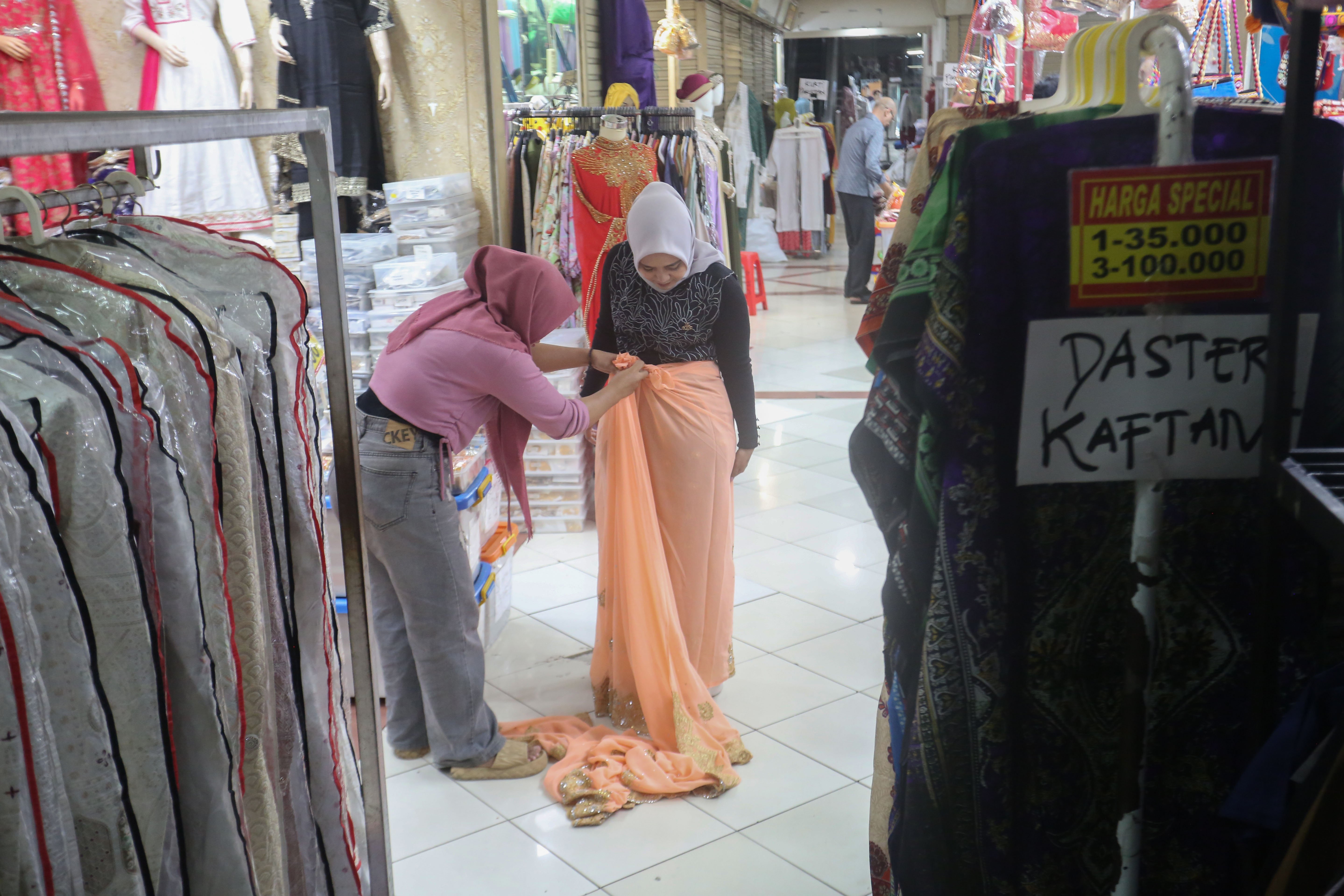 Calon pembeli mencoba kain yang dijual di Blok A Pasar Tanah Abang, Jakarta, Senin (9/3/2026). Sepuluh hari menjelang Idul Fitri 1447 Hijriah, pusat tekstil terbesar di Asia Tenggara ini terpantau mulai dipadati oleh sejumlah warga yang hendak berburu busana untuk dikenakan pada saat Hari Raya.