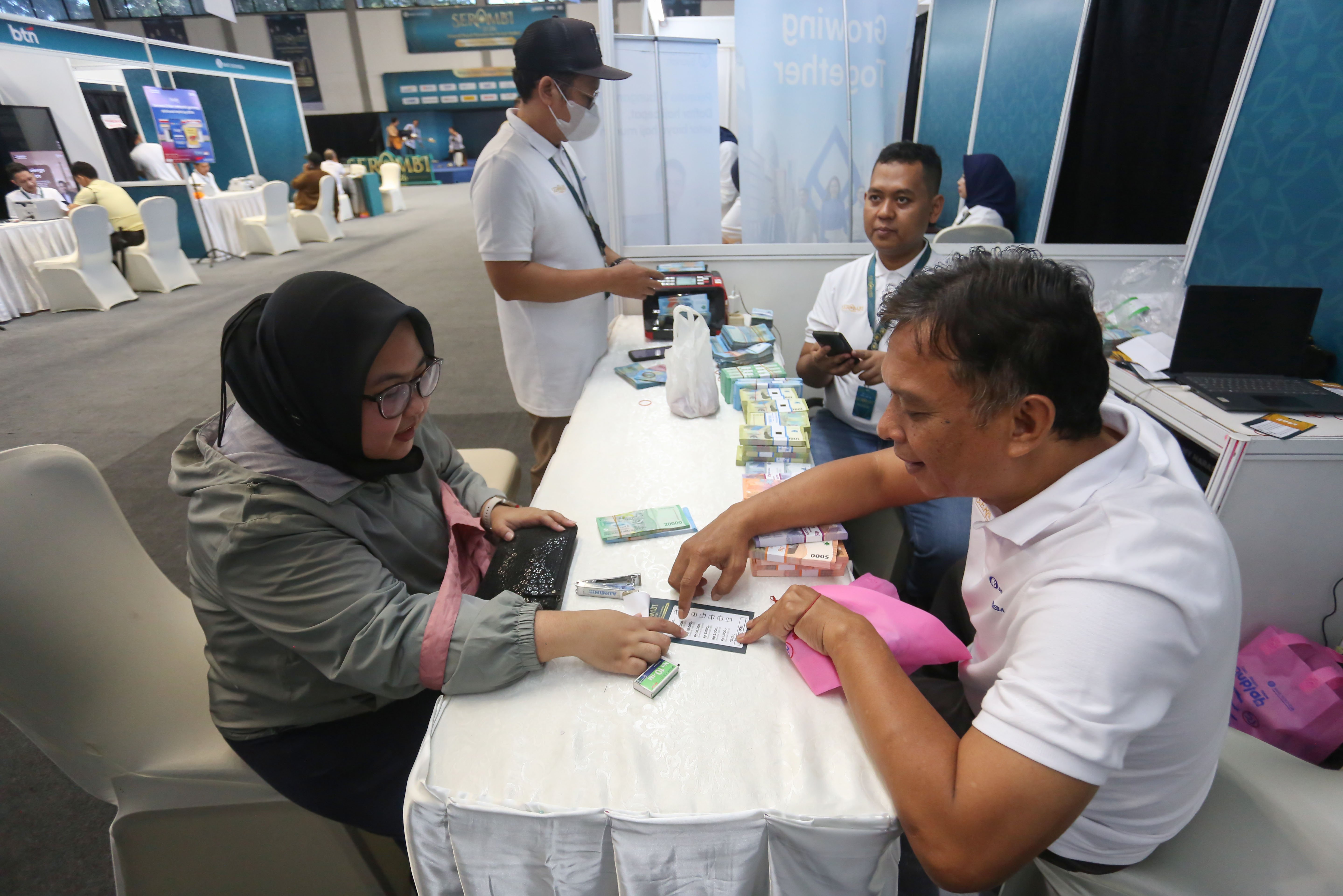 Petugas memberikan uang baru yang ditukarkan warga pada program Semarak Rupiah Ramadan dan Berkah Idul Fitri (SERAMBI) 2026 di GBK Basket Hall, Jakarta Pusat, Jumat (13/3). Bank Indonesia membuka layanan penukaran uang baru untuk keperluan Hari Raya Idul Fitri 1447 H dengan jumlah tukar maksimal Rp 5,3 juta dan kuota 5.000 orang per harinya yang digelar hingga Minggu, 15 Maret 2026.