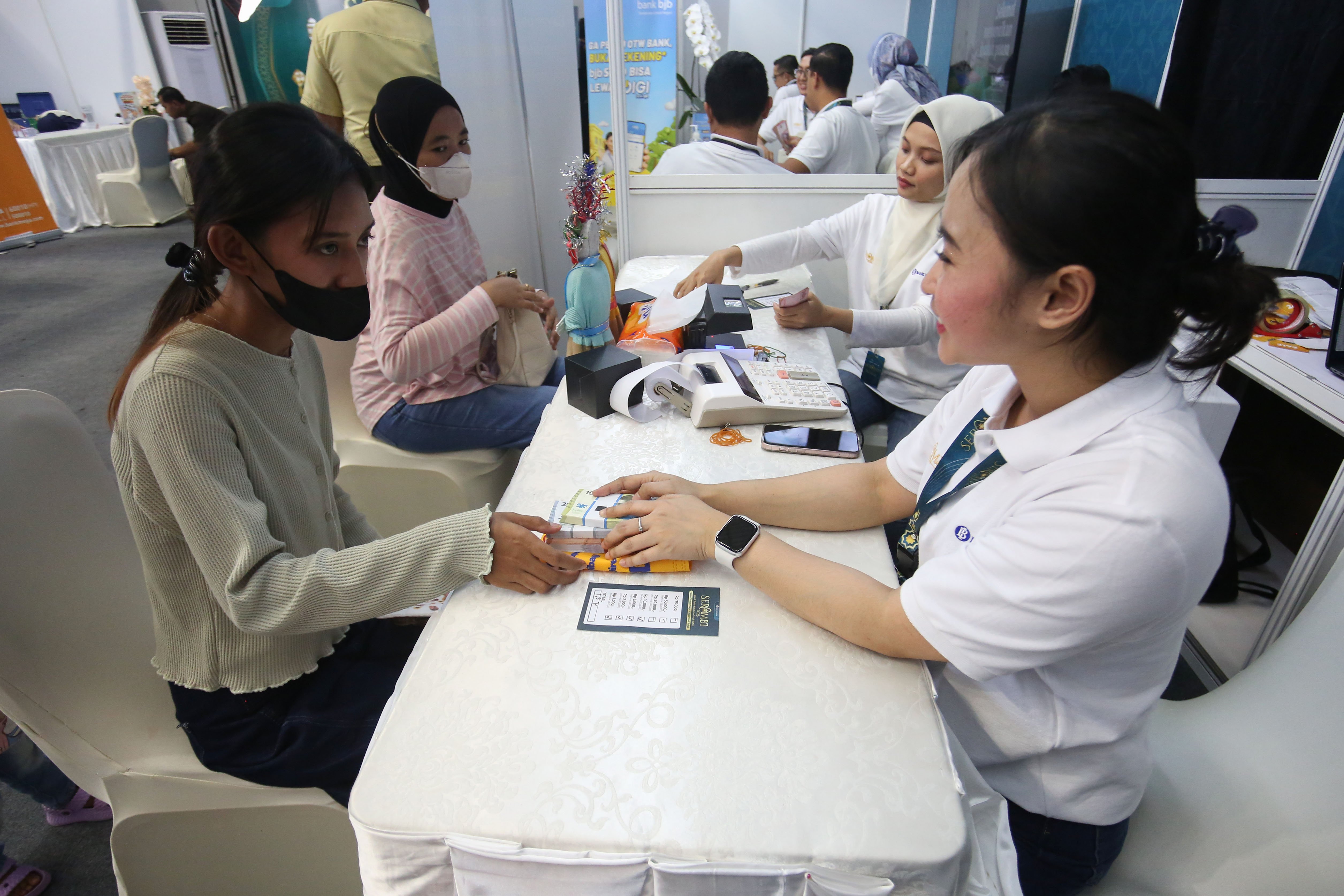 Petugas memberikan uang baru yang ditukarkan warga pada program Semarak Rupiah Ramadan dan Berkah Idul Fitri (SERAMBI) 2026 di GBK Basket Hall, Jakarta Pusat, Jumat (13/3). Bank Indonesia membuka layanan penukaran uang baru untuk keperluan Hari Raya Idul Fitri 1447 H dengan jumlah tukar maksimal Rp 5,3 juta dan kuota 5.000 orang per harinya yang digelar hingga Minggu, 15 Maret 2026.