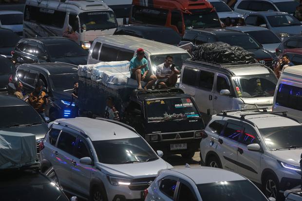 Pemudik duduk di atas kendaraannya saat antre memasuki kapal di Pelabuhan Merak, Kota Cilegon, Banten, Rabu (18/3/2026). PT ASDP Indonesia Ferry (Persero) memperkuat kesiapan layanan penyeberangan Jawa-Sumatera untuk menghadapi lonjakan pada puncak arus mudik Lebaran di antaranya dengan mengimplementasikan kebijakan sistem penundaan (delaying sistem) di sejumlah titik kantong parkir (buffer zone) guna meminimalisasi penumpukan kendaraan di pelabuhan.