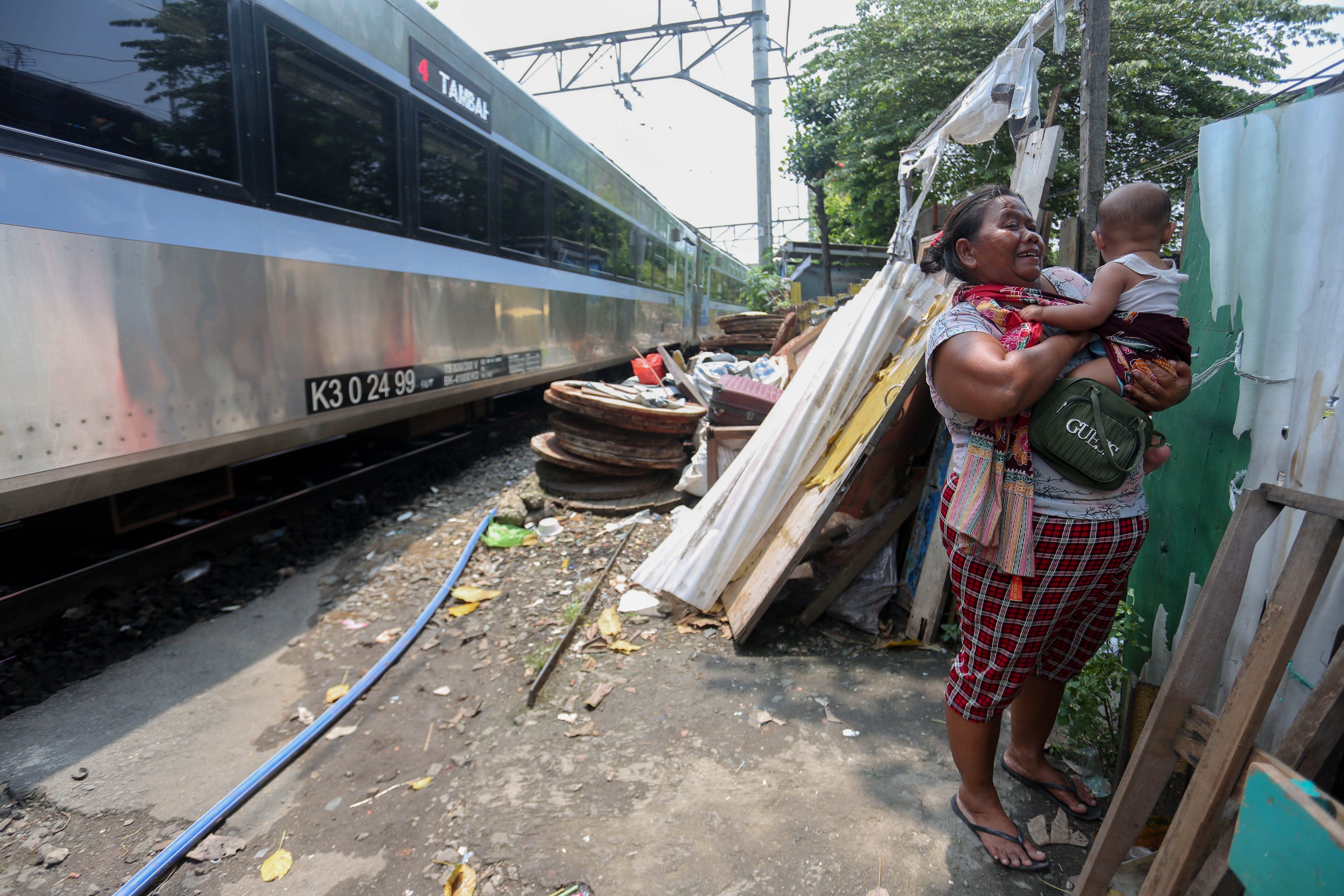 Seorang warga bersama cucunya berada di dekat tempat tinggalnya di bantaran rel kereta api, kawasan Senen, Jakarta Pusat, Senin (30/3/2026). Presiden Prabowo Subianto menyatakan bahwa akan membangun hunian layak bagi warga yang tinggal di pinggir rel kawasan tersebut.
