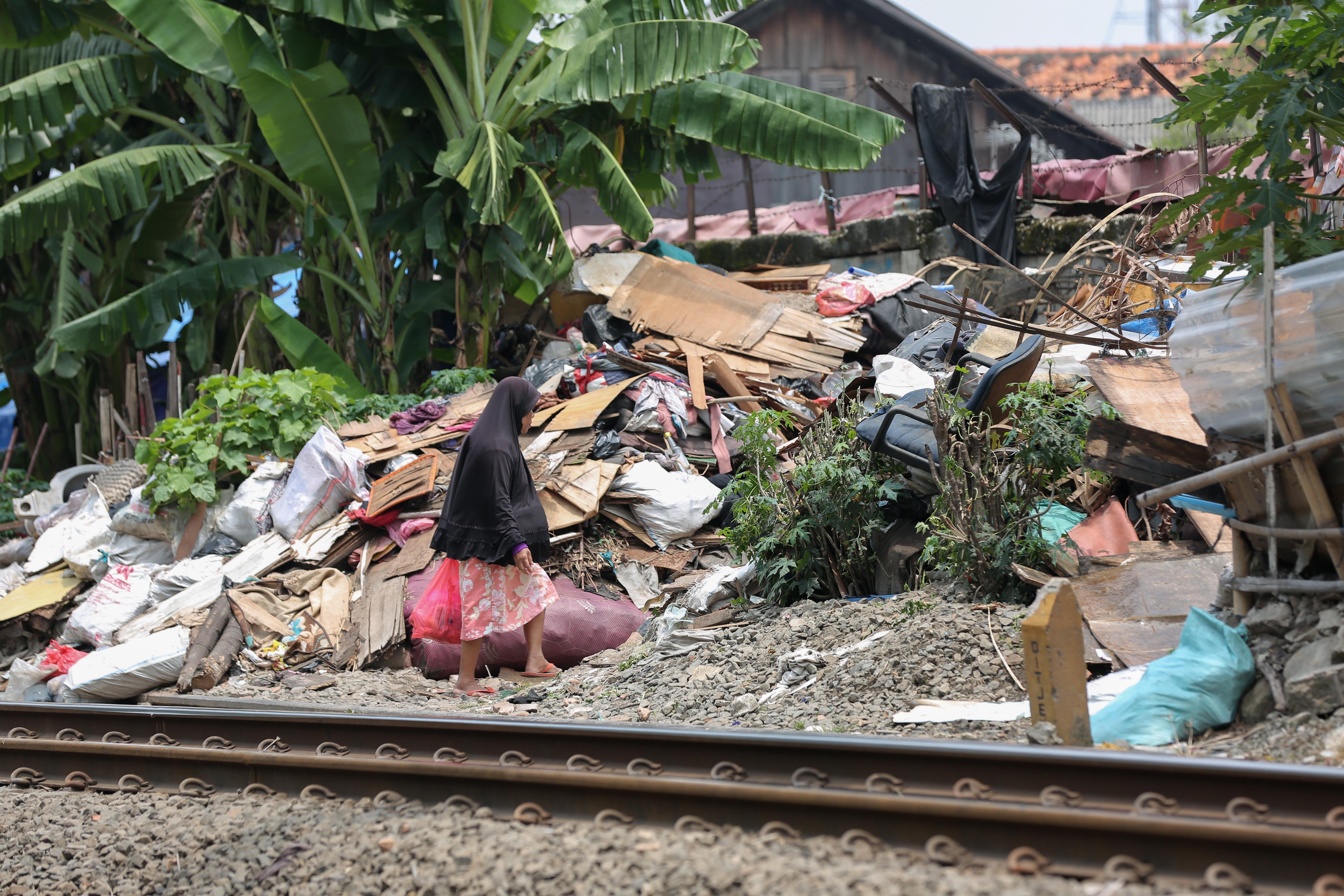 Warga berjalan di dekat tempat tinggalnya di bantaran rel kereta api, kawasan Senen, Jakarta Pusat, Senin (30/3/2026). Presiden Prabowo Subianto menyatakan bahwa akan membangun hunian layak bagi warga yang tinggal di pinggir rel kawasan tersebut.