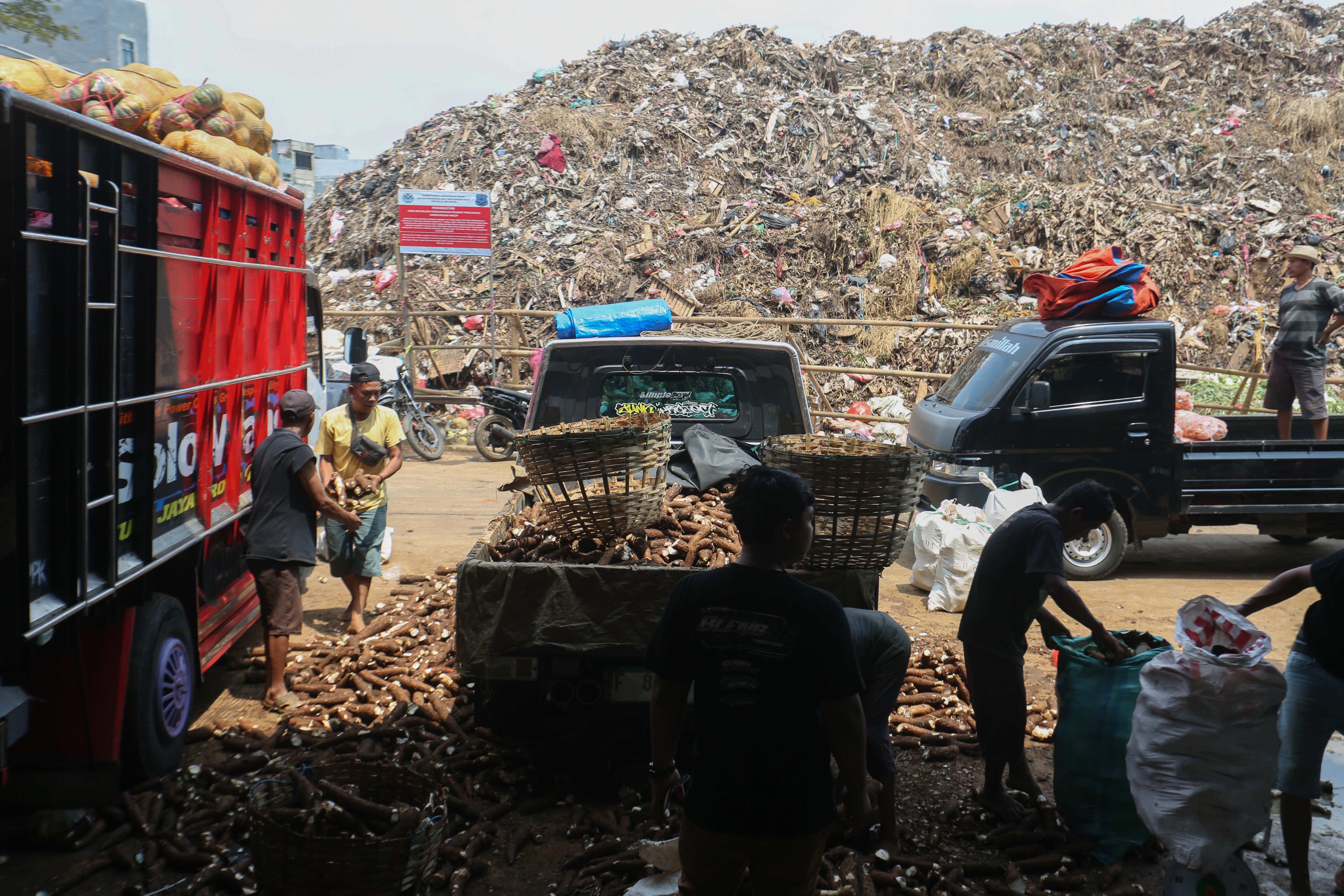 Pedagang beraktivitas dengan latar belakang tumpukan sampah di Pasar Induk Kramat Jati, Jakarta Timur, Rabu (1/4/2026). Keterbatasan kuota pembuangan ke Tempat Pengolahan Sampah Terpadu (TPST) Bantar Gebang pascainsiden longsor yang terjadi membuat sampah menumpuk di Pasar Induk Kramat Jati. 