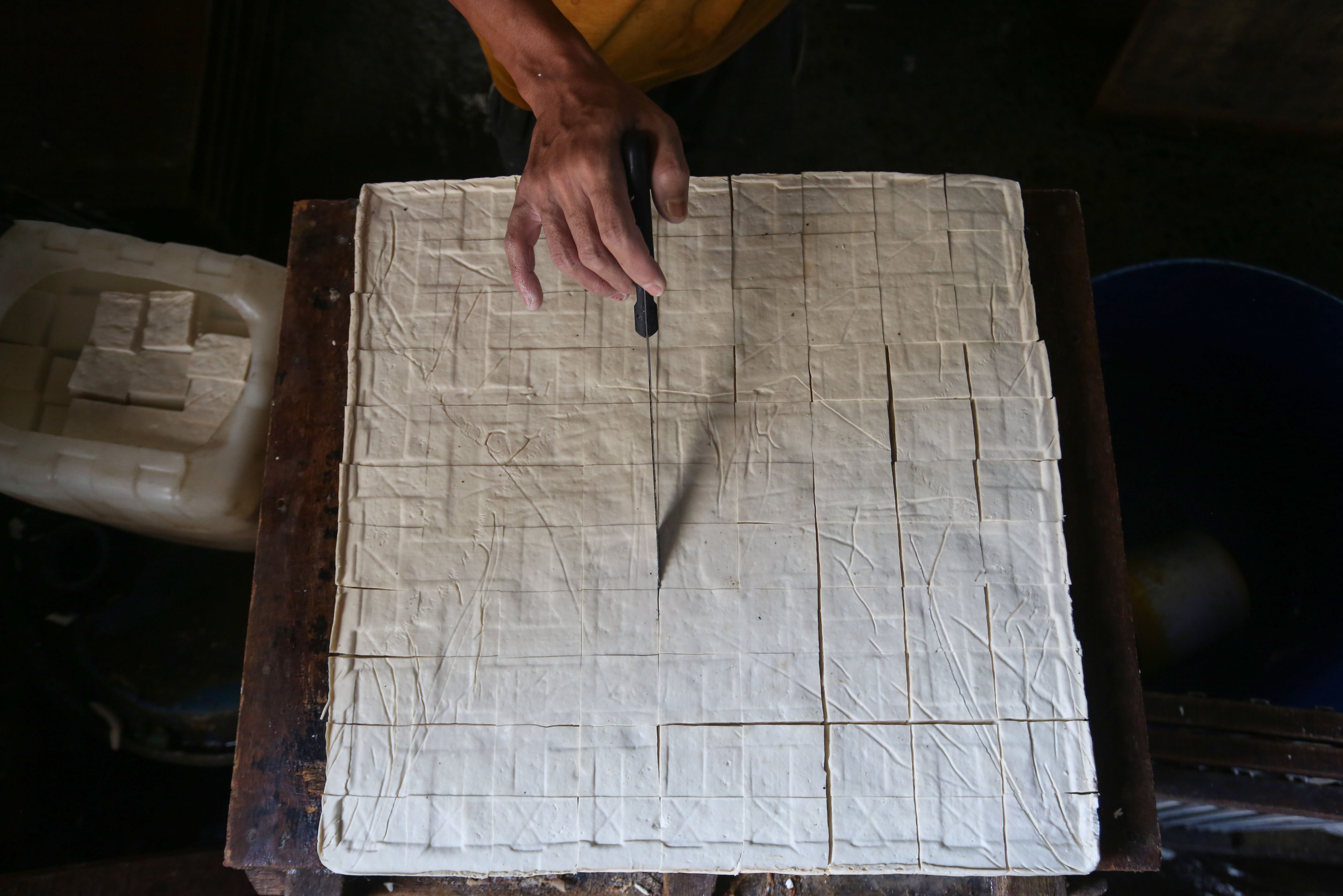 Pekerja menyelesaikan pembuatan tahu di rumah produksi tahu kawasan Duren Tiga, Jakarta, Senin (13/4/2026). Kenaikan harga kedelai dari Rp 8.600 hingga Rp 11.000 per kilogramnya membuat pengrajin mengurangi ukuran tahu guna mencegah kenaikan harga jual ke pasar sehingga daya beli konsumen dapat terjaga.