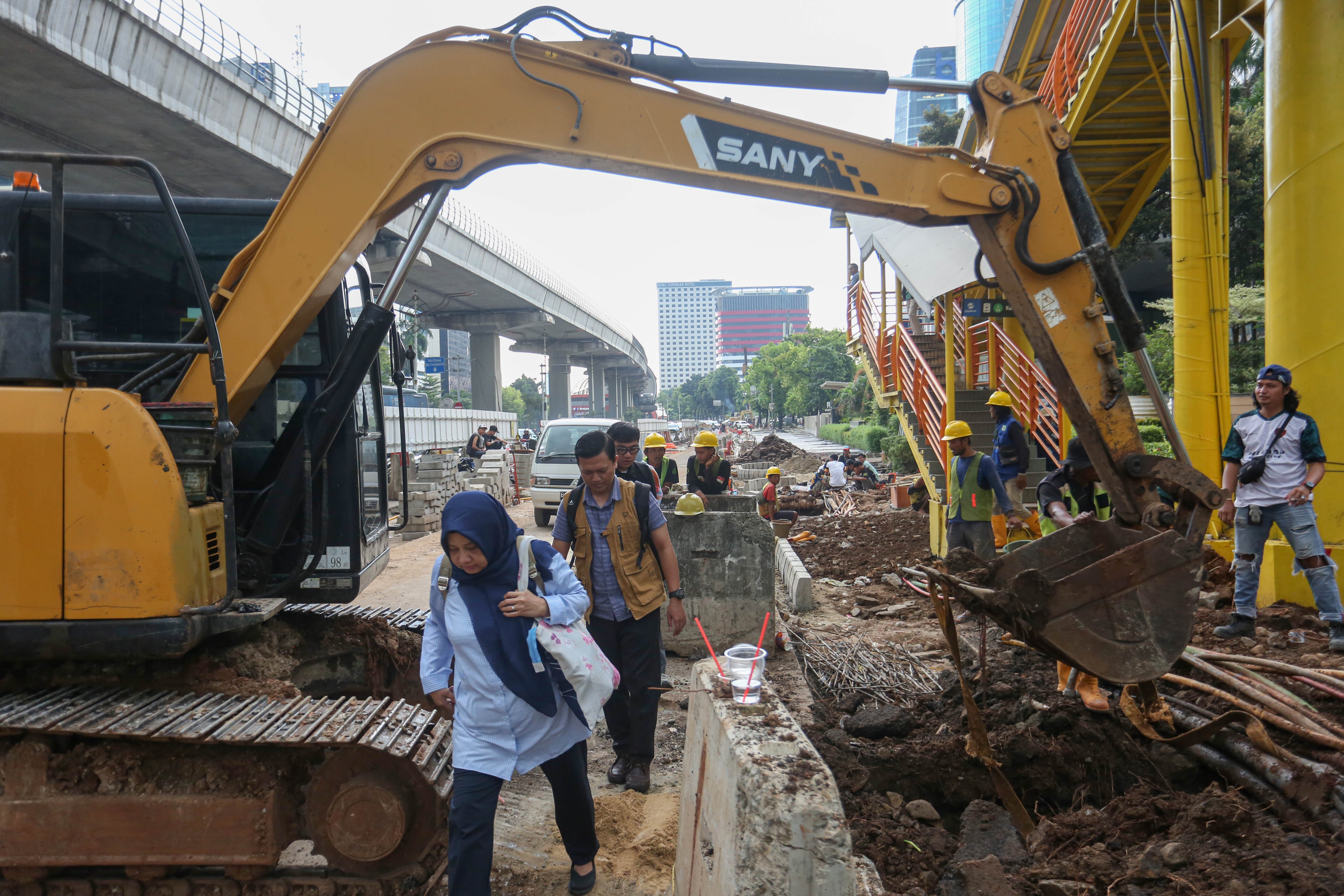 Pejalan kaki melintas di dekat proyek revitalisasi Jalan H.R. Rasuna Said, Kuningan, Jakarta Selatan, Selasa (14/4/2026). Penataan jalan sepanjang 3,65 kilometer yang dimulai dari Jalan Gembira hingga Simpang Kuningan itu bertujuan untuk membuat ruang bersama yang inklusif dengan memperhatikan seluruh pengguna jalan mulai dari pejalan kaki, pesepeda, pengguna transportasi umum hingga kendaraan bermotor.