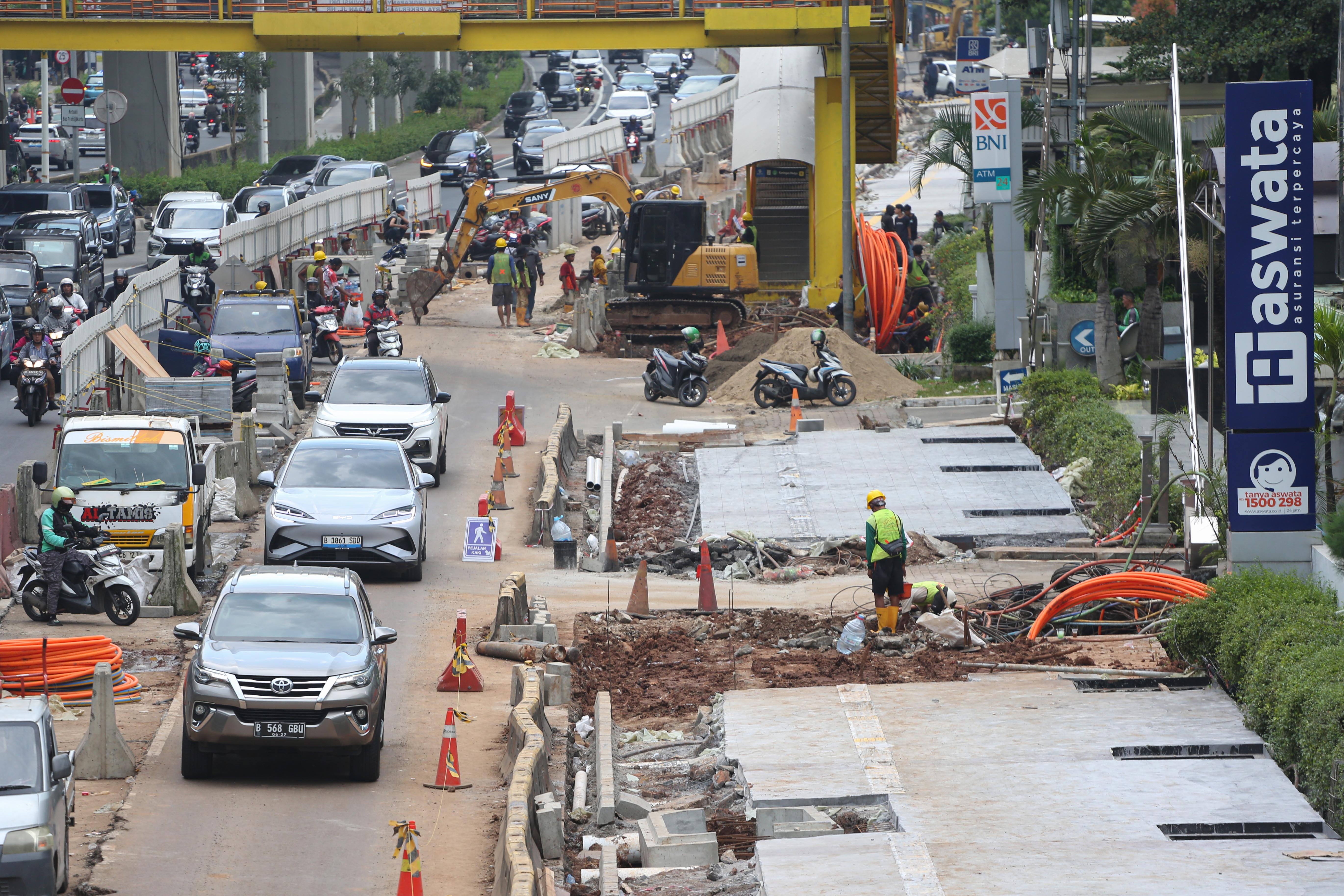 Pengendara mobil dan sepeda motor melintas di dekat proyek revitalisasi Jalan H.R. Rasuna Said, Kuningan, Jakarta Selatan, Selasa (14/4/2026). Penataan jalan sepanjang 3,65 kilometer yang dimulai dari Jalan Gembira hingga Simpang Kuningan itu bertujuan untuk membuat ruang bersama yang inklusif dengan memperhatikan seluruh pengguna jalan mulai dari pejalan kaki, pesepeda, pengguna transportasi umum hingga kendaraan bermotor.
