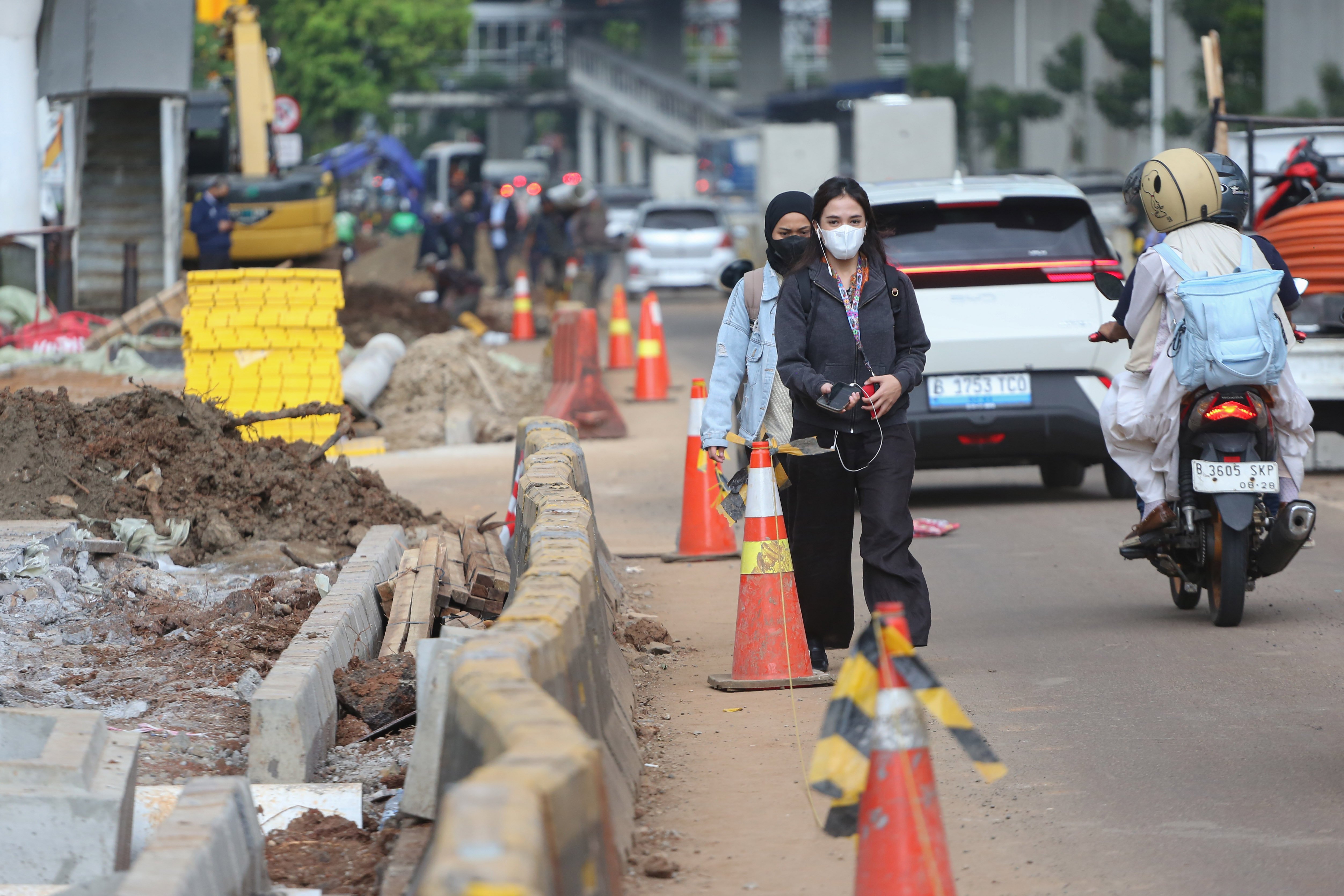 Pejalan kaki dan pengendara sepeda motor melintas di dekat proyek revitalisasi Jalan H.R. Rasuna Said, Kuningan, Jakarta Selatan, Selasa (14/4/2026). Penataan jalan sepanjang 3,65 kilometer yang dimulai dari Jalan Gembira hingga Simpang Kuningan itu bertujuan untuk membuat ruang bersama yang inklusif dengan memperhatikan seluruh pengguna jalan mulai dari pejalan kaki, pesepeda, pengguna transportasi umum hingga kendaraan bermotor.