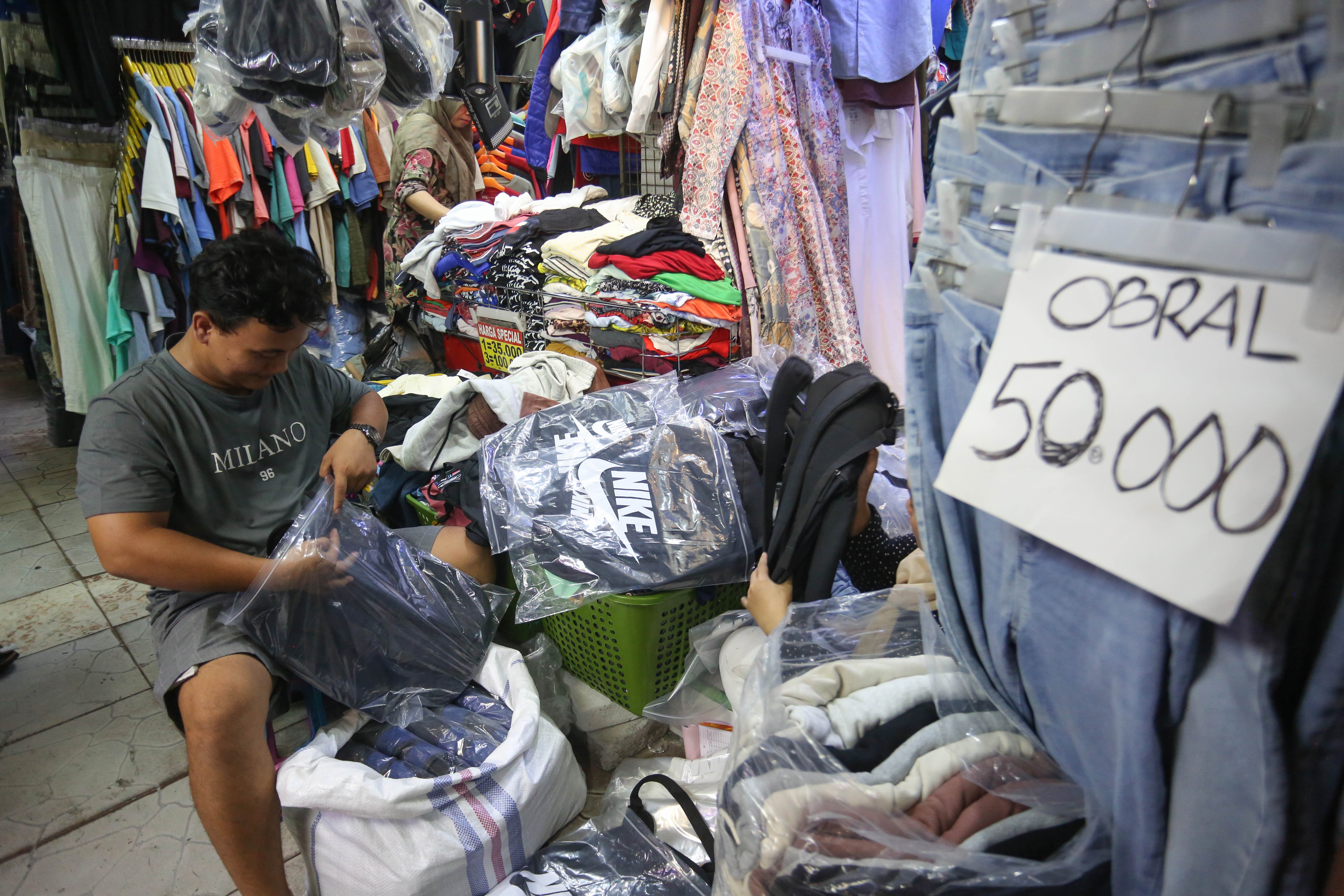 Pedagang mengemas tas untuk dikirimkan kepada pembeli di Pasar Ular, Koja, Jakarta Utara, Jumat (17/4/2026). Berdasarkan penuturan pedagang, sejak pandemi Covid-19 dan munculnya platform belanja online membuat penjualan barang dagangan di pasar tersebut menurun hingga 50 persen.