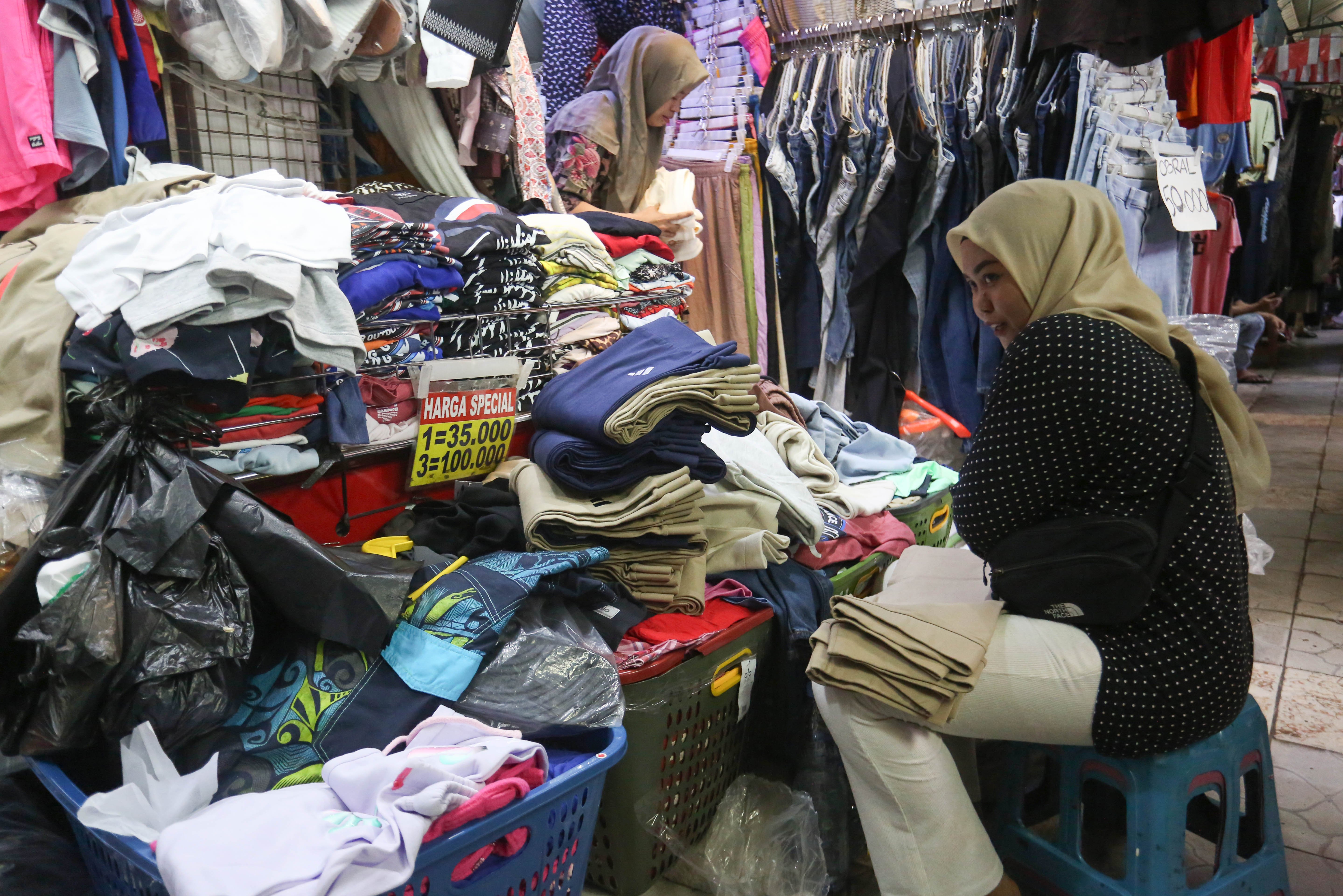 Pedagang merapikan pakaian yang dijual di Pasar Ular, Koja, Jakarta Utara, Jumat (17/4/2026). Berdasarkan penuturan pedagang, sejak pandemi Covid-19 dan munculnya platform belanja online membuat penjualan barang dagangan di pasar tersebut menurun hingga 50 persen.