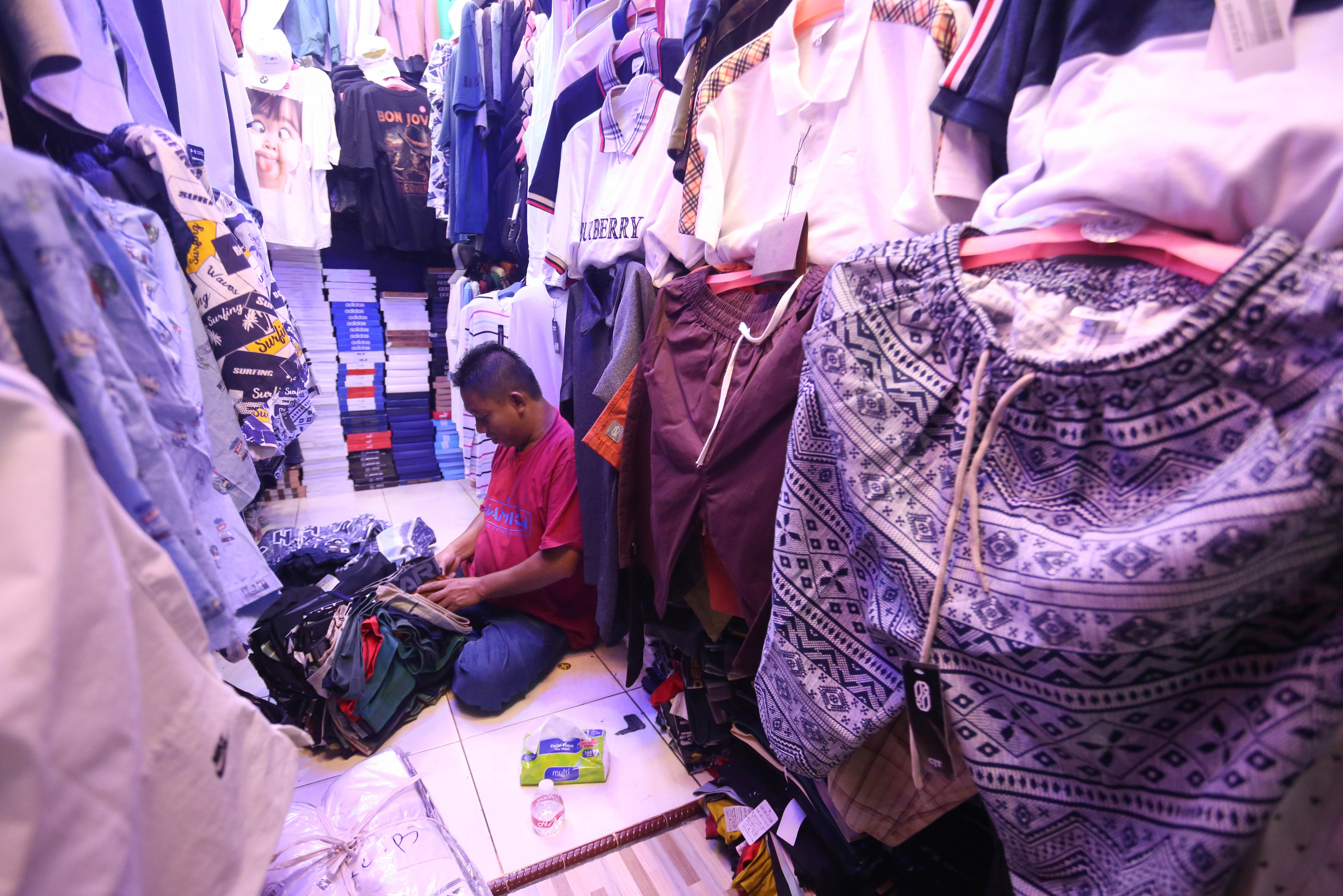 Pedagang mengemas pakaian yang dijual di Pasar Ular, Koja, Jakarta Utara, Jumat (17/4/2026). Berdasarkan penuturan pedagang, sejak pandemi Covid-19 dan munculnya platform belanja online membuat penjualan barang dagangan di pasar tersebut menurun hingga 50 persen.