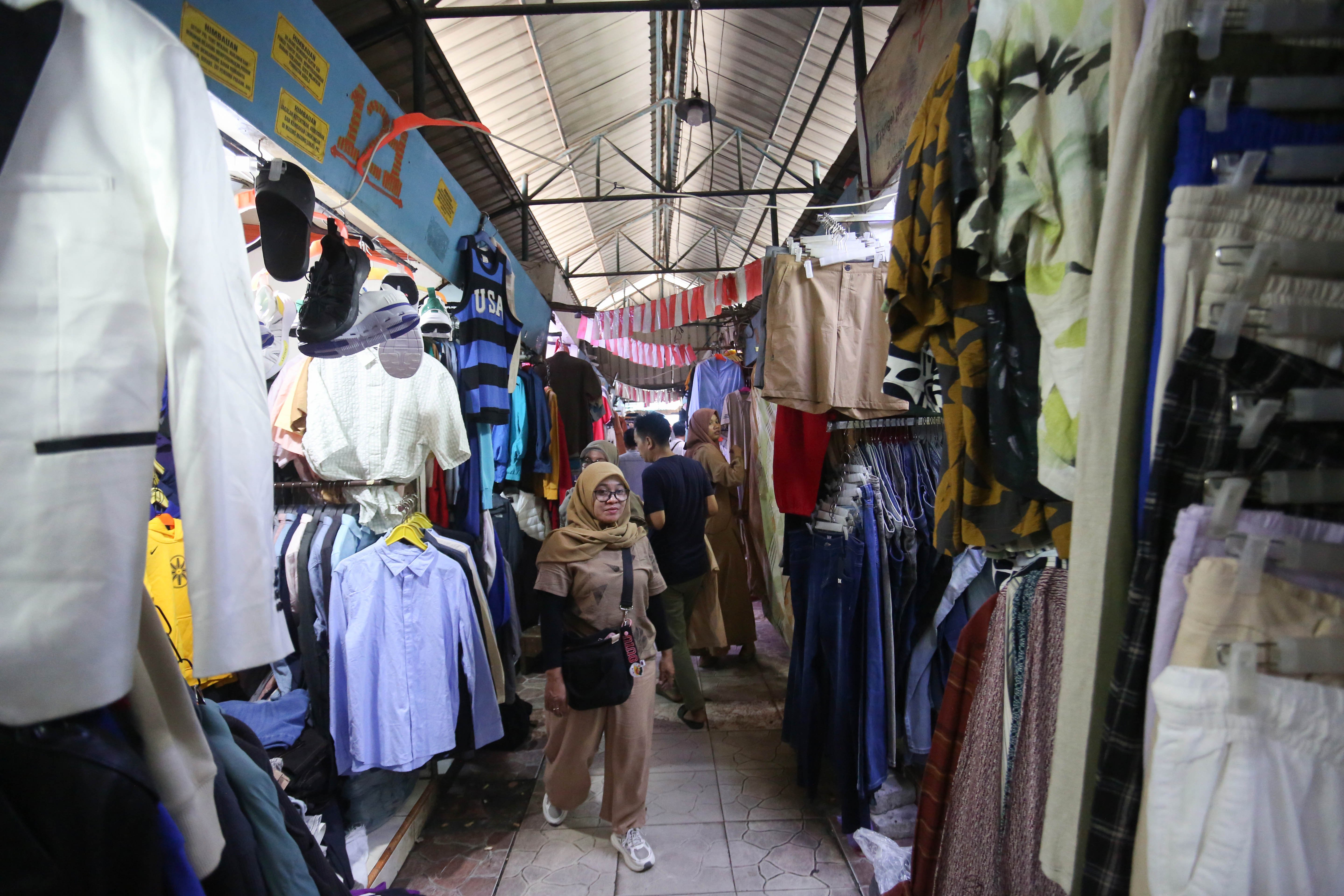 Calon pembeli melihat pakaian yang dijual di Pasar Ular, Koja, Jakarta Utara, Jumat (17/4/2026). Berdasarkan penuturan pedagang, sejak pandemi Covid-19 dan munculnya platform belanja online membuat penjualan barang dagangan di pasar tersebut menurun hingga 50 persen.