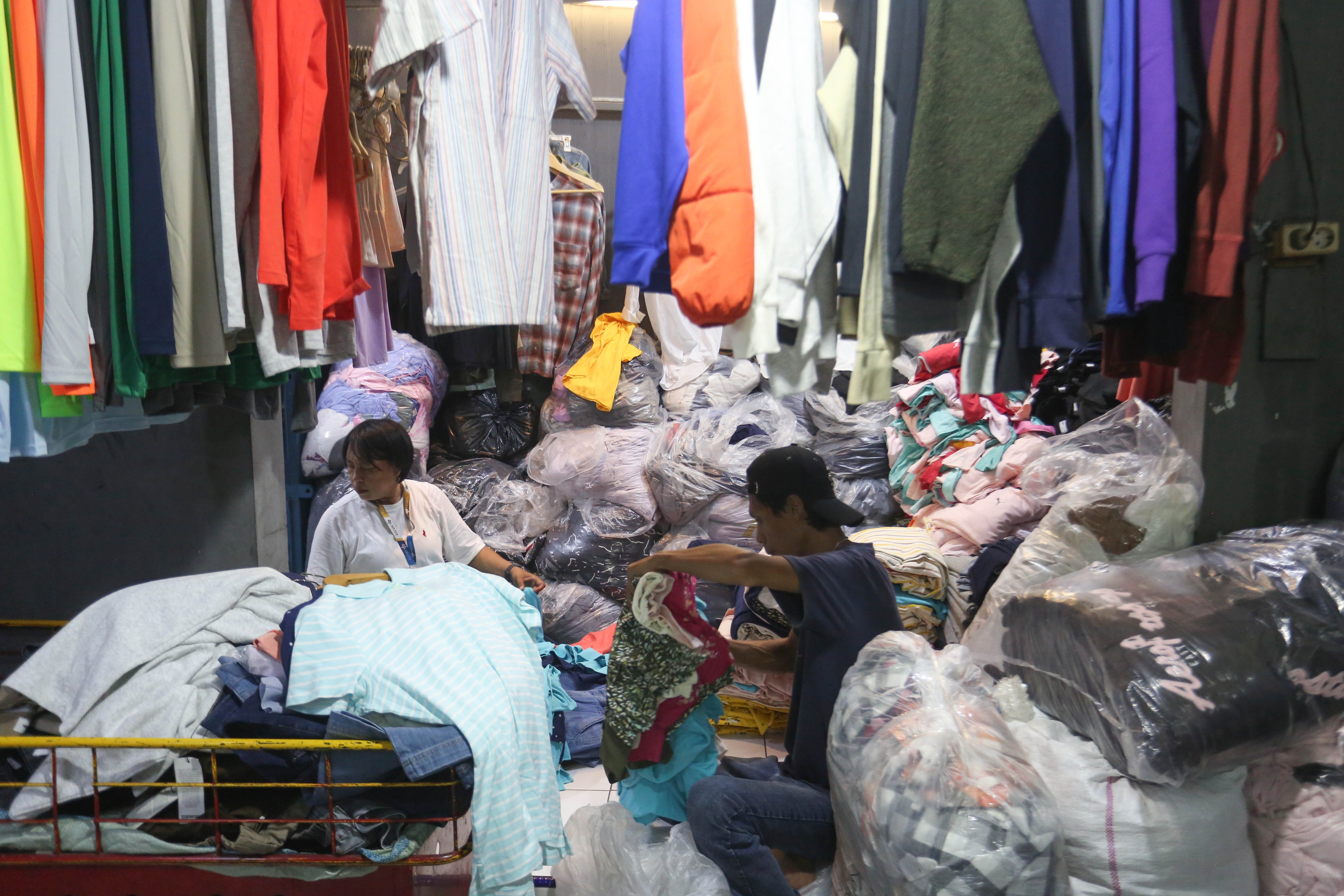 Pedagang mengemas pakaian yang dijual di Pasar Ular, Koja, Jakarta Utara, Jumat (17/4/2026). Berdasarkan penuturan pedagang, sejak pandemi Covid-19 dan munculnya platform belanja online membuat penjualan barang dagangan di pasar tersebut menurun hingga 50 persen.