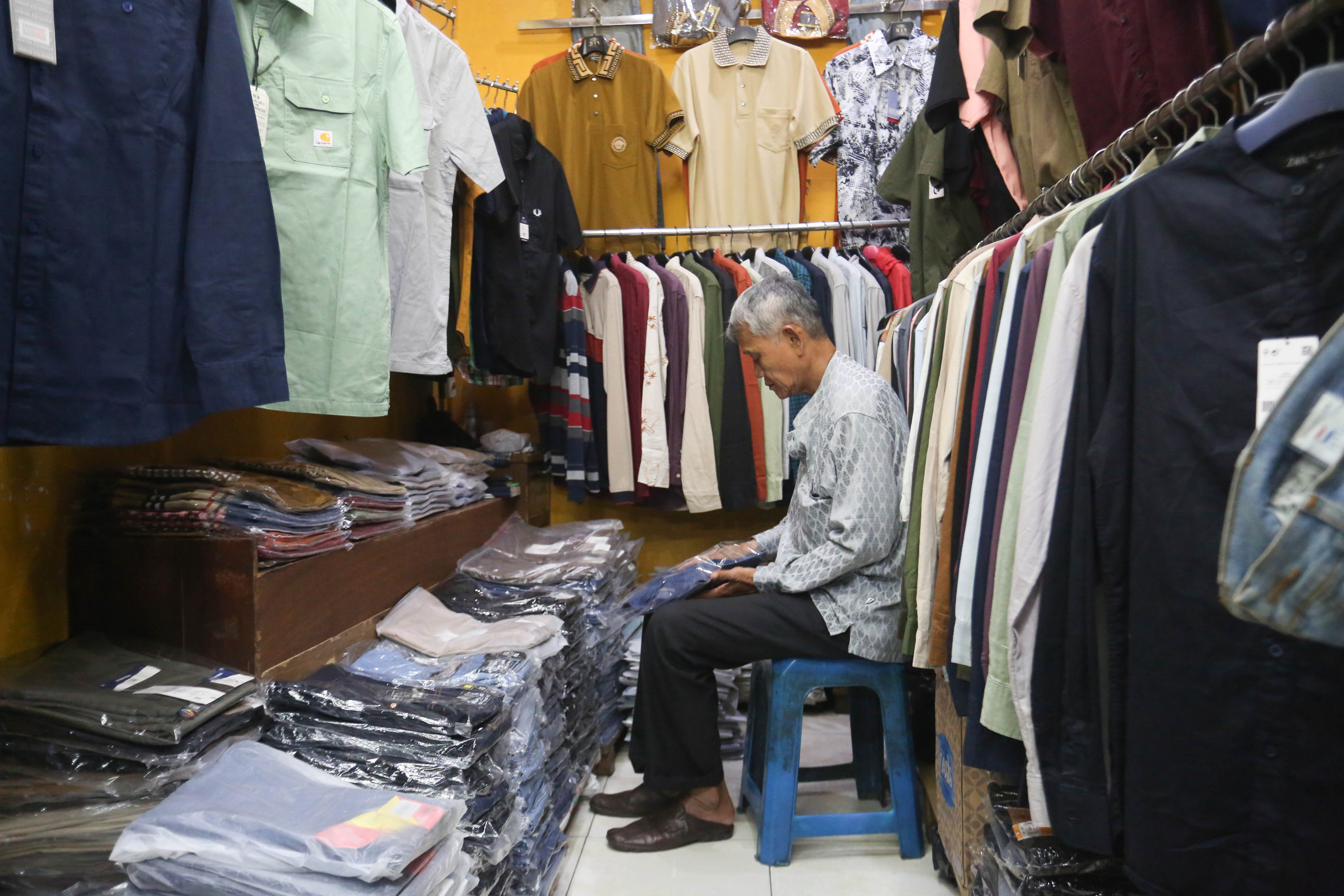 Pedagang mengemas pakaian yang dijual di Pasar Ular, Koja, Jakarta Utara, Jumat (17/4/2026). Berdasarkan penuturan pedagang, sejak pandemi Covid-19 dan munculnya platform belanja online membuat penjualan barang dagangan di pasar tersebut menurun hingga 50 persen.