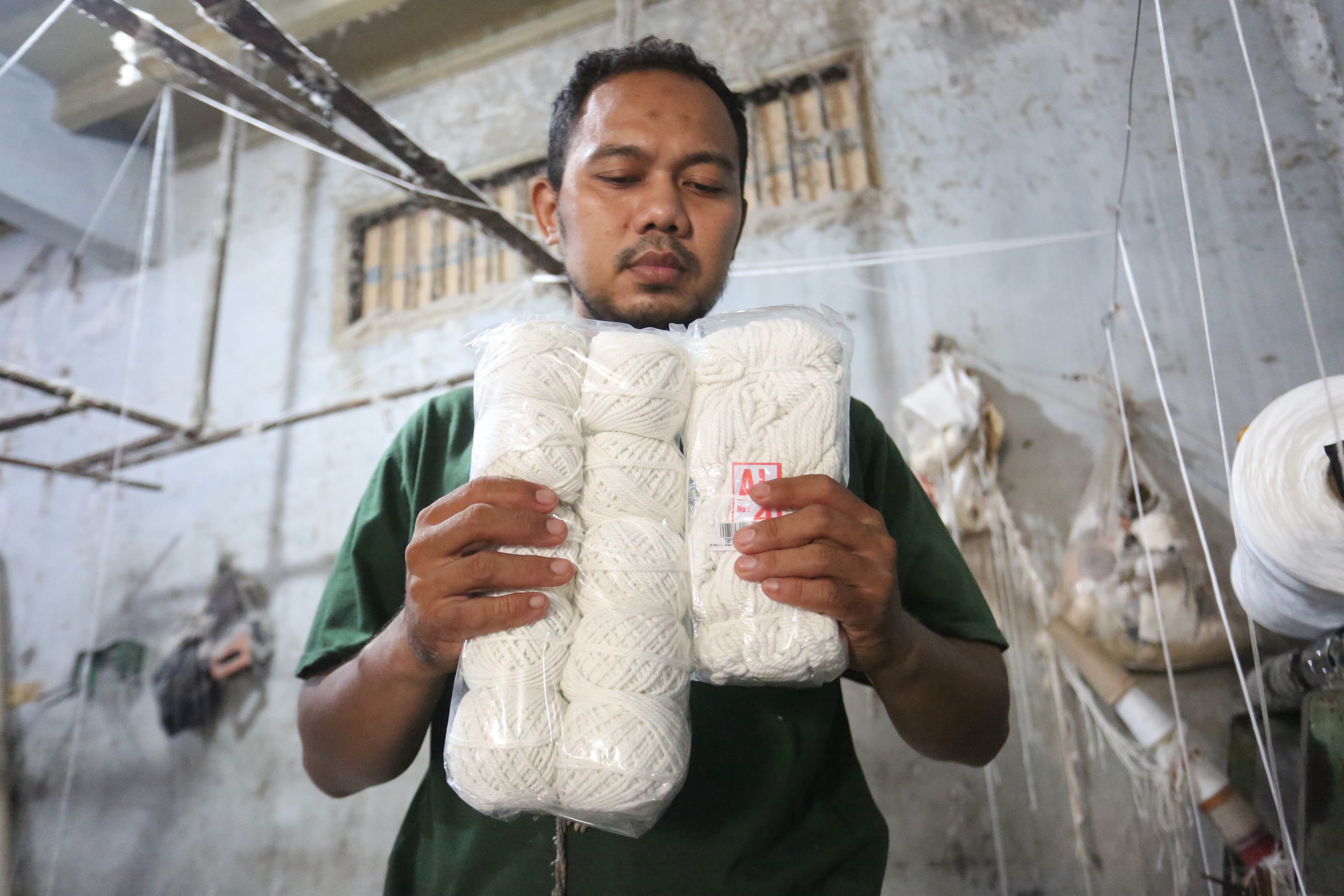 Pekerja menunjukkan benang yang diproduksi di Kebayoran Lama, Jakarta, Selasa (21/4/2026). Berdasarkan keterangan Saprudin (60) selaku pemilik usaha tersebut, harga bahan baku utama poliester yang melonjak berimbas pada naiknya harga benang katun dan poliester yang diproduksi ditempatnya mengalami kenaikan hingga Rp.2000 per kilogram.