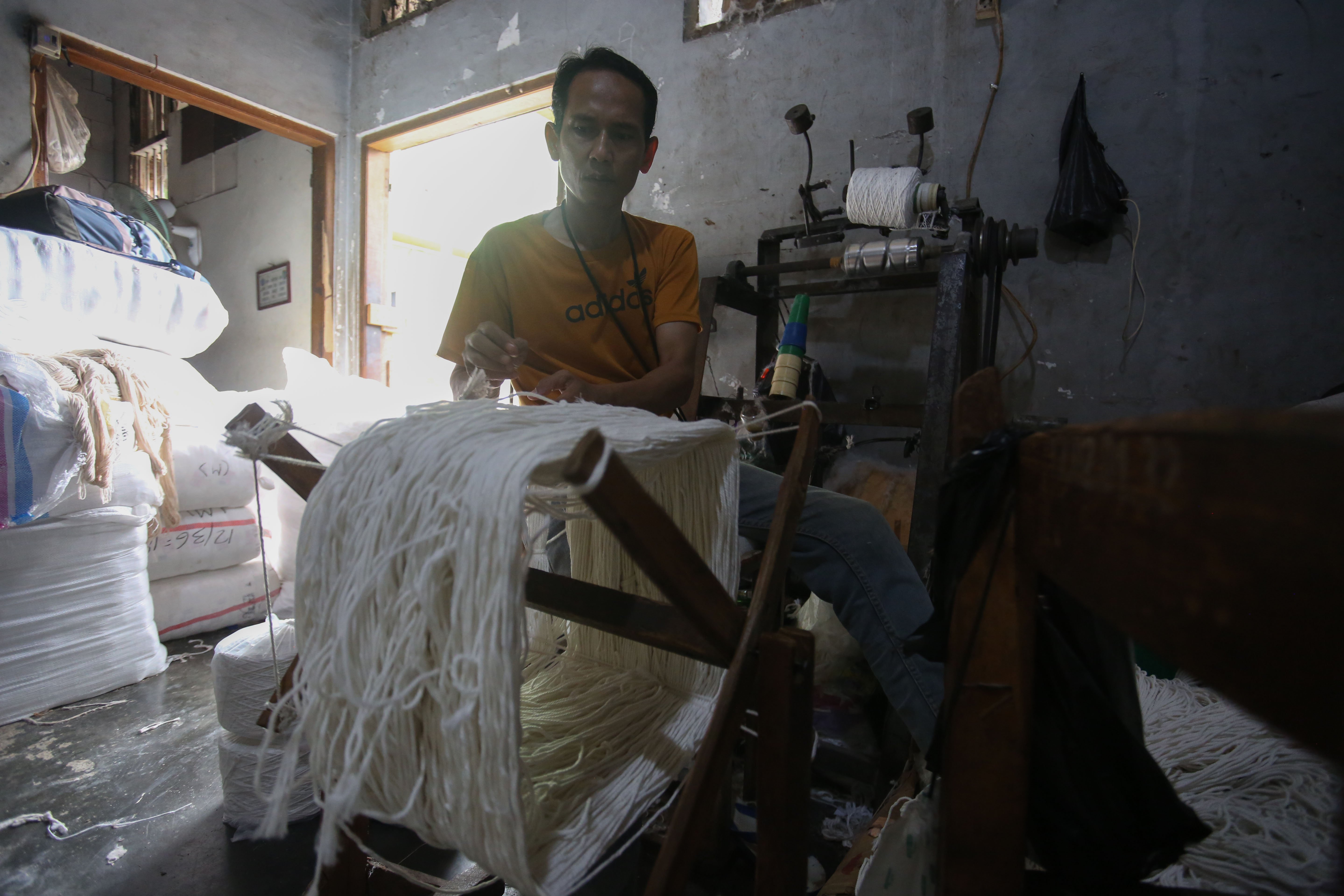 Pekerja memintal benang di Kebayoran Lama, Jakarta, Selasa (21/4/2026). Berdasarkan keterangan Saprudin (60) selaku pemilik usaha tersebut, harga bahan baku utama poliester yang melonjak berimbas pada naiknya harga benang katun dan poliester yang diproduksi ditempatnya mengalami kenaikan hingga Rp.2000 per kilogram.