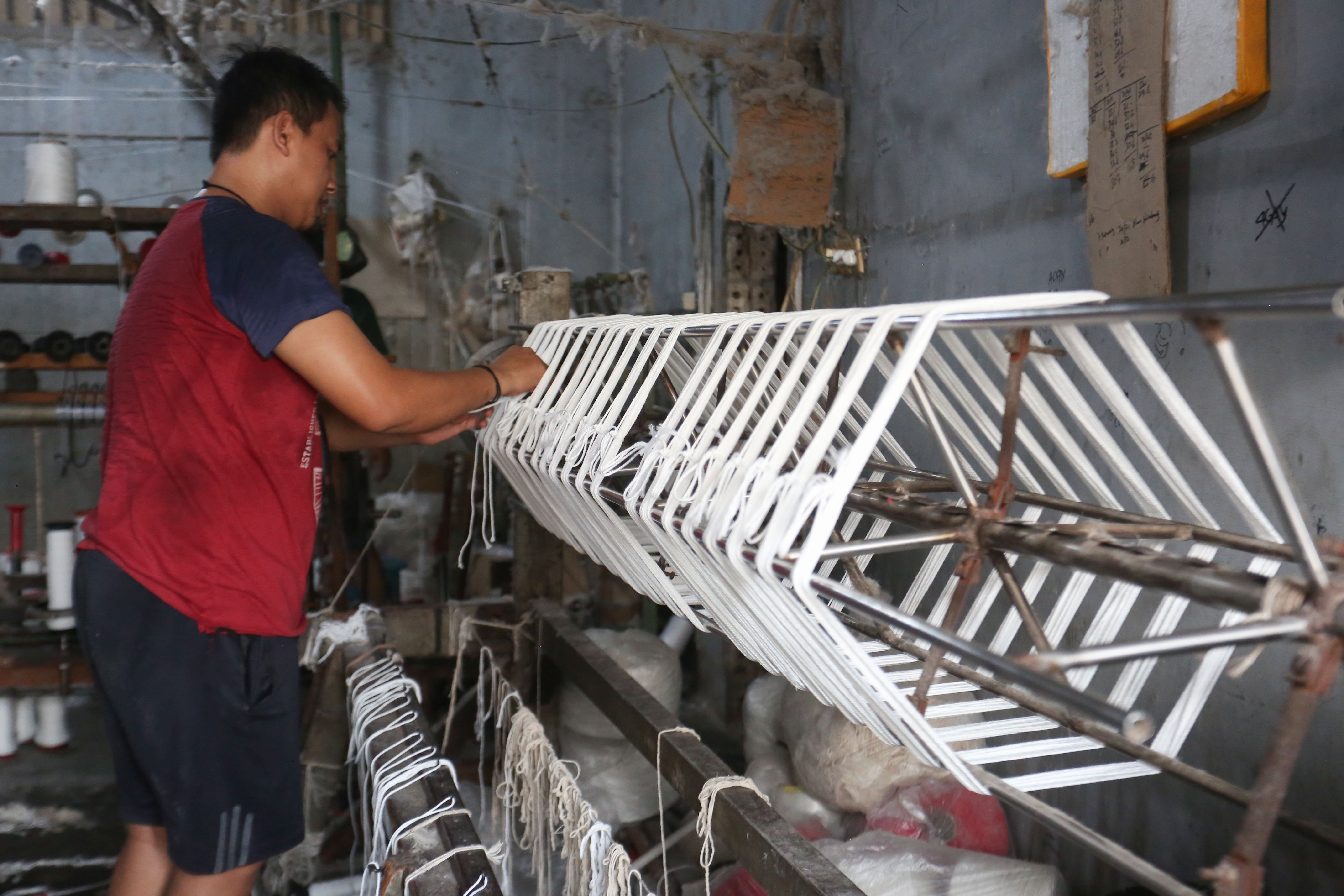 Pekerja memintal benang di Kebayoran Lama, Jakarta, Selasa (21/4/2026). Berdasarkan keterangan Saprudin (60) selaku pemilik usaha tersebut, harga bahan baku utama poliester yang melonjak berimbas pada naiknya harga benang katun dan poliester yang diproduksi ditempatnya mengalami kenaikan hingga Rp.2000 per kilogram.