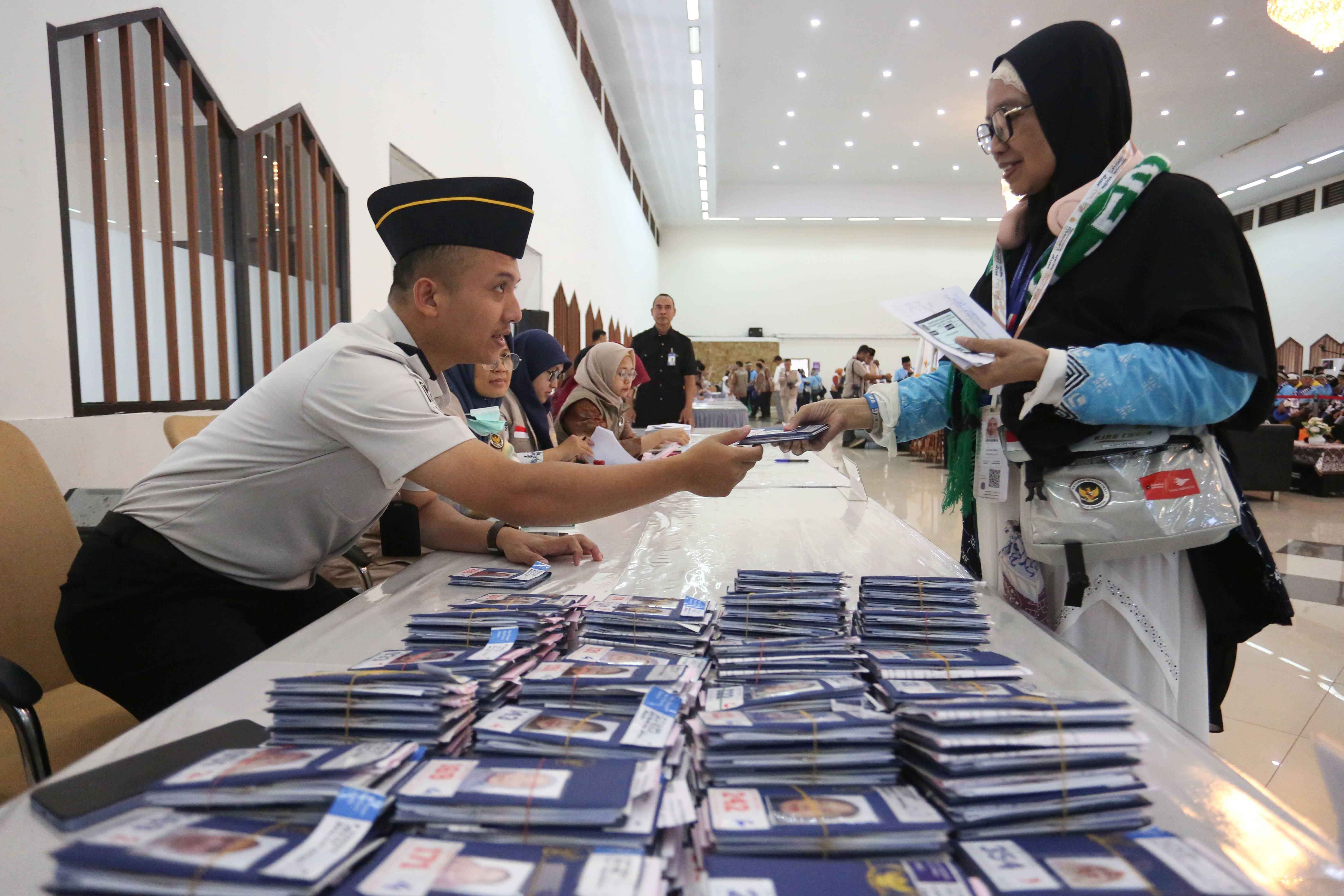 Petugas imigrasi memberikan paspor kepada jamaah calon haji di Asrama Haji Pondok Gede, Jakarta, Selasa (21/4/2026). Sebanyak 393 jamaah calon haji kloter pertama asal Jakarta mengikuti pemeriksaan administrasi dan kesehatan sebelum diberangkatkan ke tanah suci pada 22 April 2026.