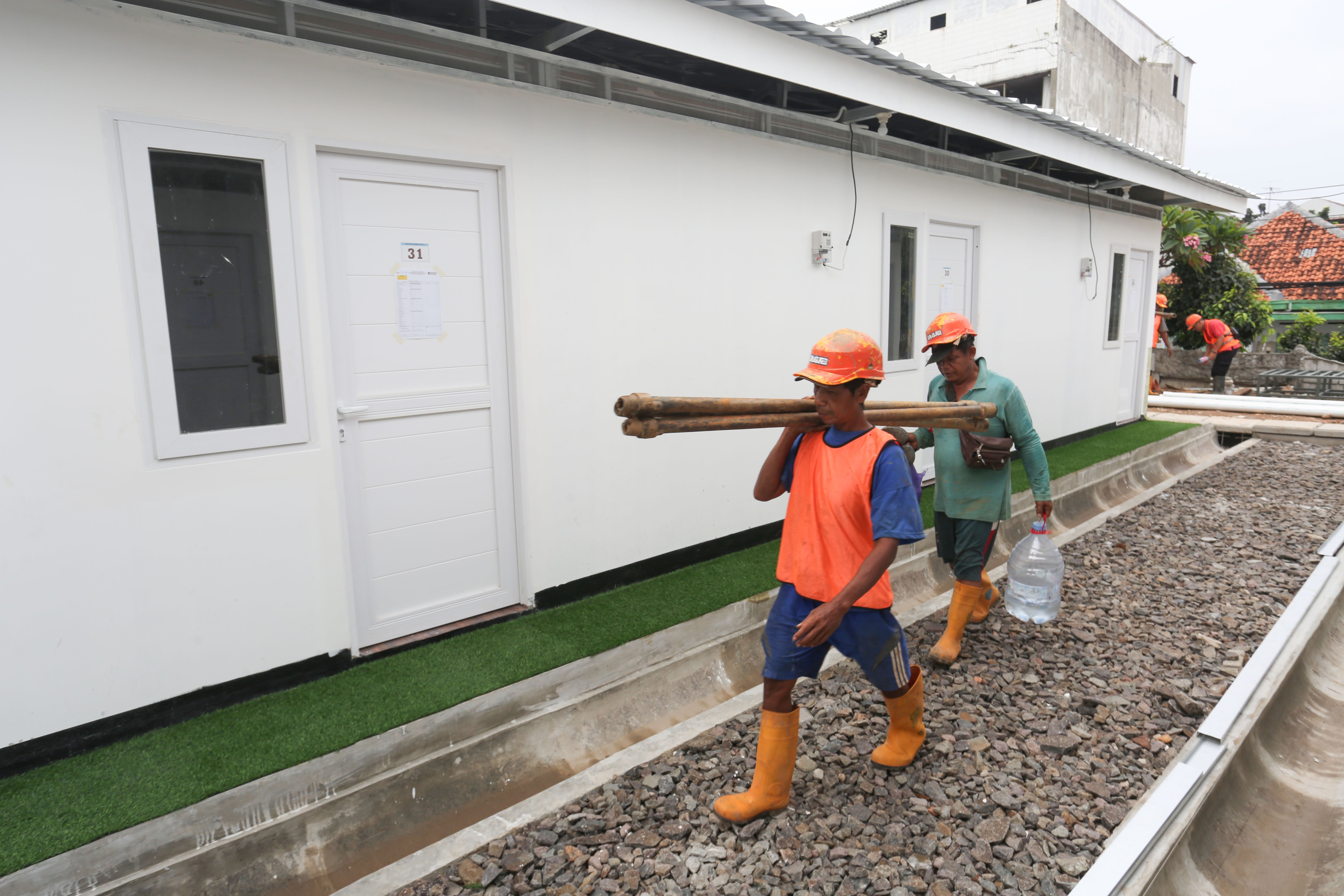 Pekerja mengangkut alat kerja untuk menyelesaikan pembangunan hunian layak di kawasan Senen, Jakarta, Kamis (23/4/2026). Kementerian Perumahan dan Kawasan Permukiman (PKP) membangun 324 unit rumah yang dilengkapi fasilitas seperti dapur umum, toilet komunal dan musala untuk warga yang tinggal di bantaran rel kereta api Pasar Senen.