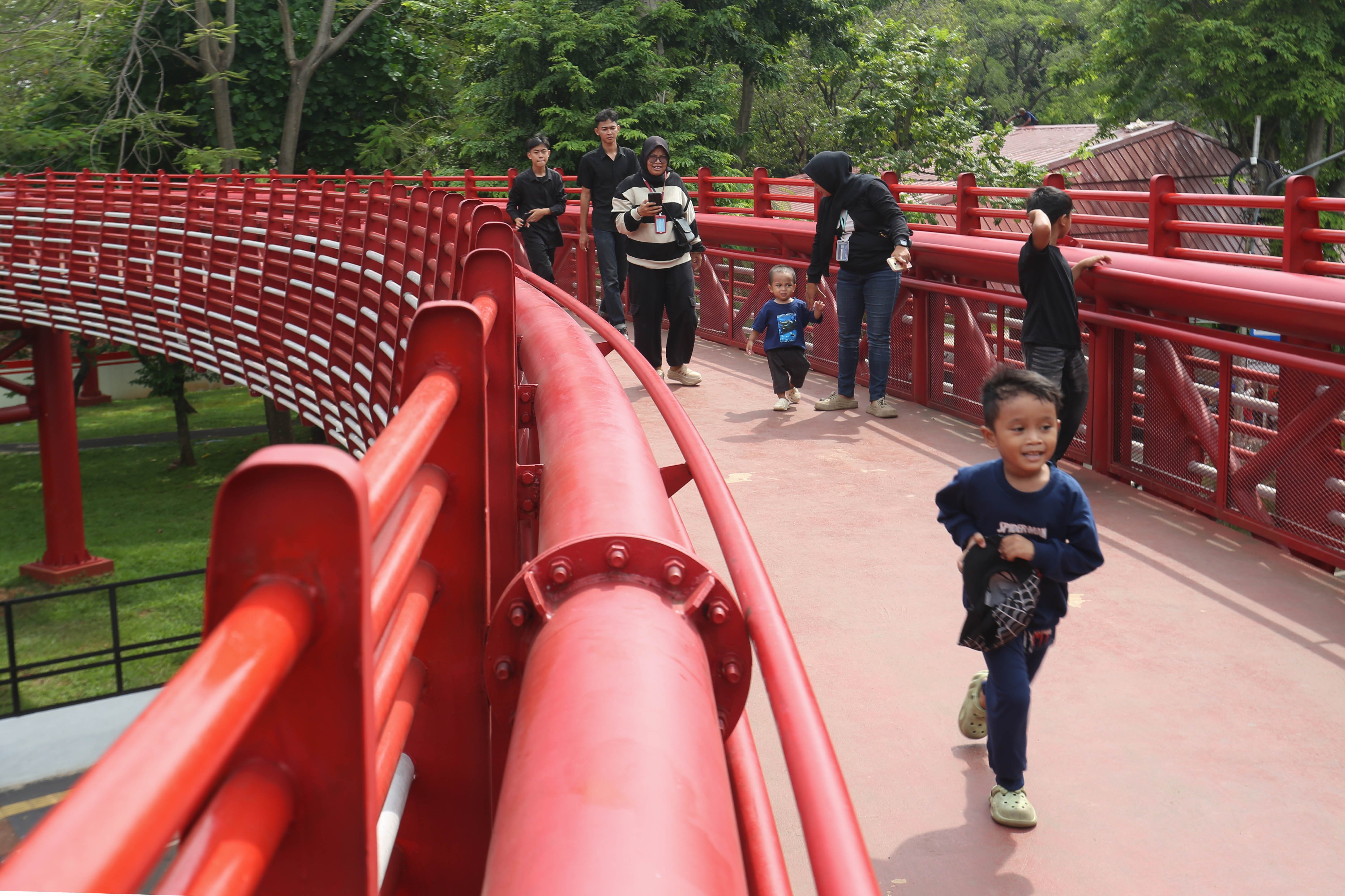 Warga berjalan di jembatan Taman Bendera Pusaka, Kebayoran Baru, Jakarta Selatan, Sabtu (25/4/2026). Taman seluas 5,6 hektare yang menawarkan suasana asri dan dilengkapi dengan fasilitas seperti area piknik, lapangan olahraga, hingga tempat bermain anak ini menjadi destinasi wisata baru bagi masyarakat dalam menghabiskan waktu akhir pekan.