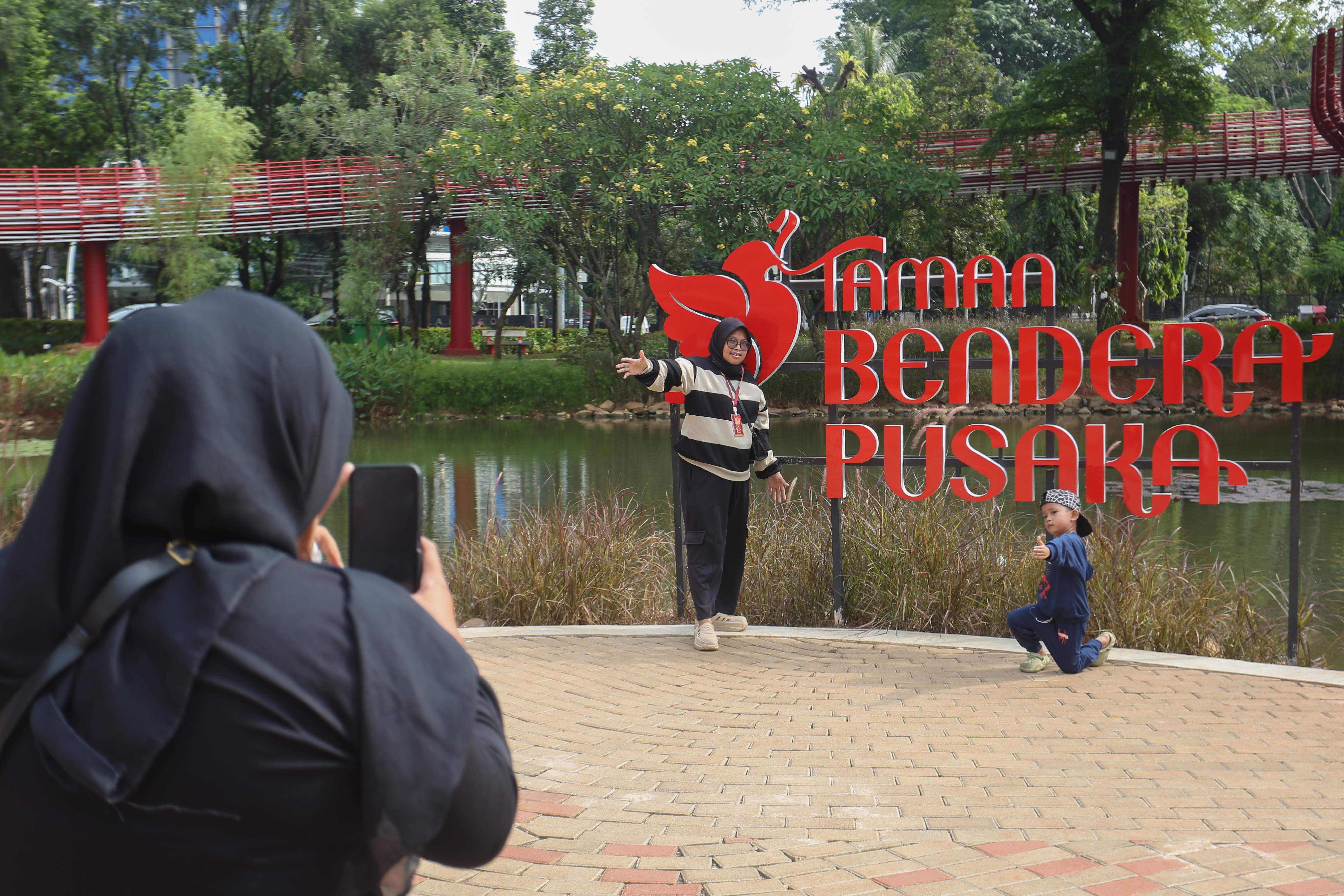 Warga berfoto di Taman Bendera Pusaka, Kebayoran Baru, Jakarta Selatan, Sabtu (25/4/2026). Taman seluas 5,6 hektare yang menawarkan suasana asri dan dilengkapi dengan fasilitas seperti area piknik, lapangan olahraga, hingga tempat bermain anak ini menjadi destinasi wisata baru bagi masyarakat dalam menghabiskan waktu akhir pekan.