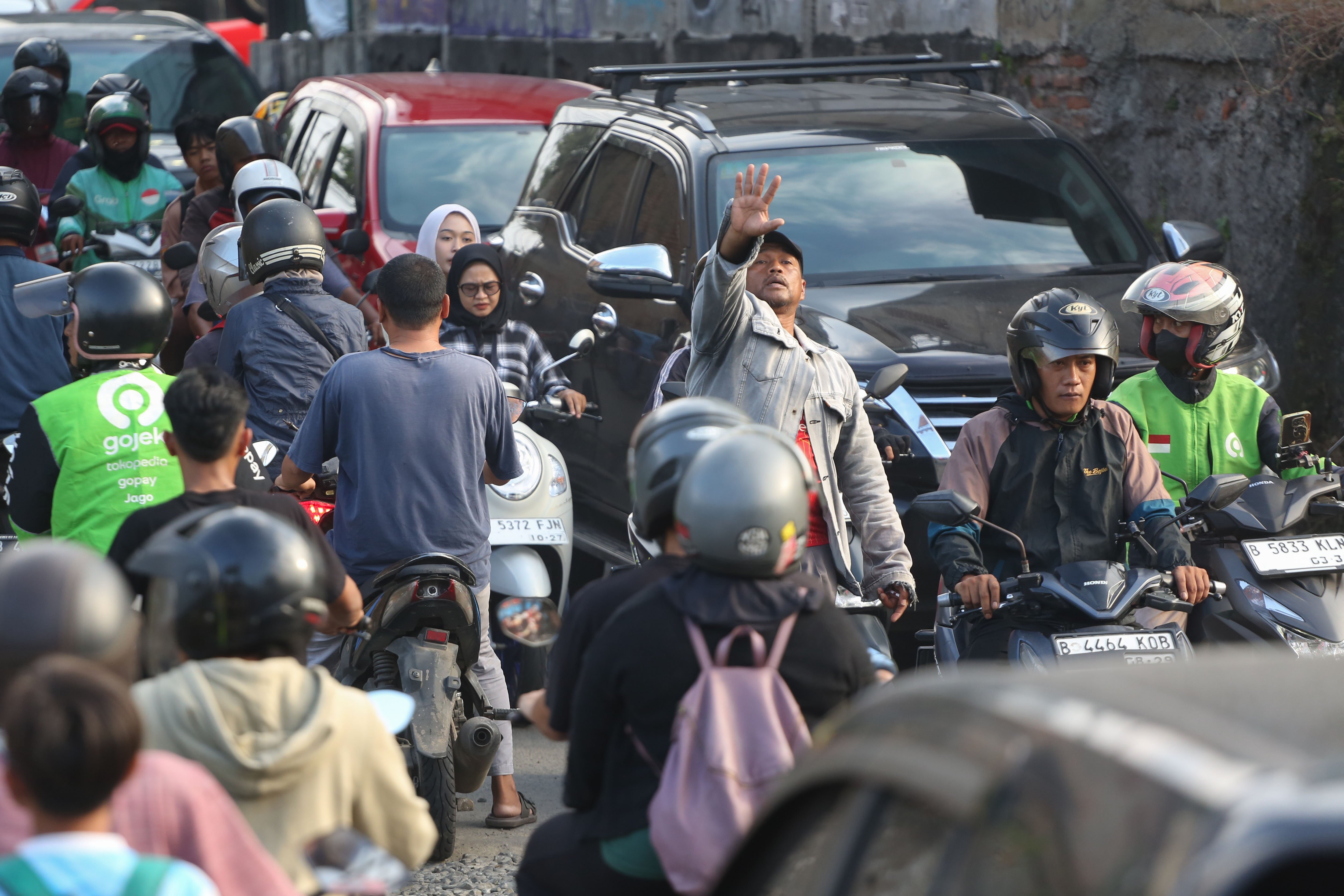 Warga mengatur pengendara yang melintas di perlintasan kereta api sebidang di Jalan Ampera, Kota Bekasi, Jawa Barat, Senin (27/4/2026). PT Kereta Api Indonesia (KAI) Persero menyatakan akan menutup berbagai jalur perlintasan kereta api sebidang yang tidak memenuhi syarat keselamatan menyusul dua tragedi yang melibatkan KRL Commuter Line dengan Taksi Green SM dan KA Argo Bromo Anggrek dengan KRL Commuter Line.