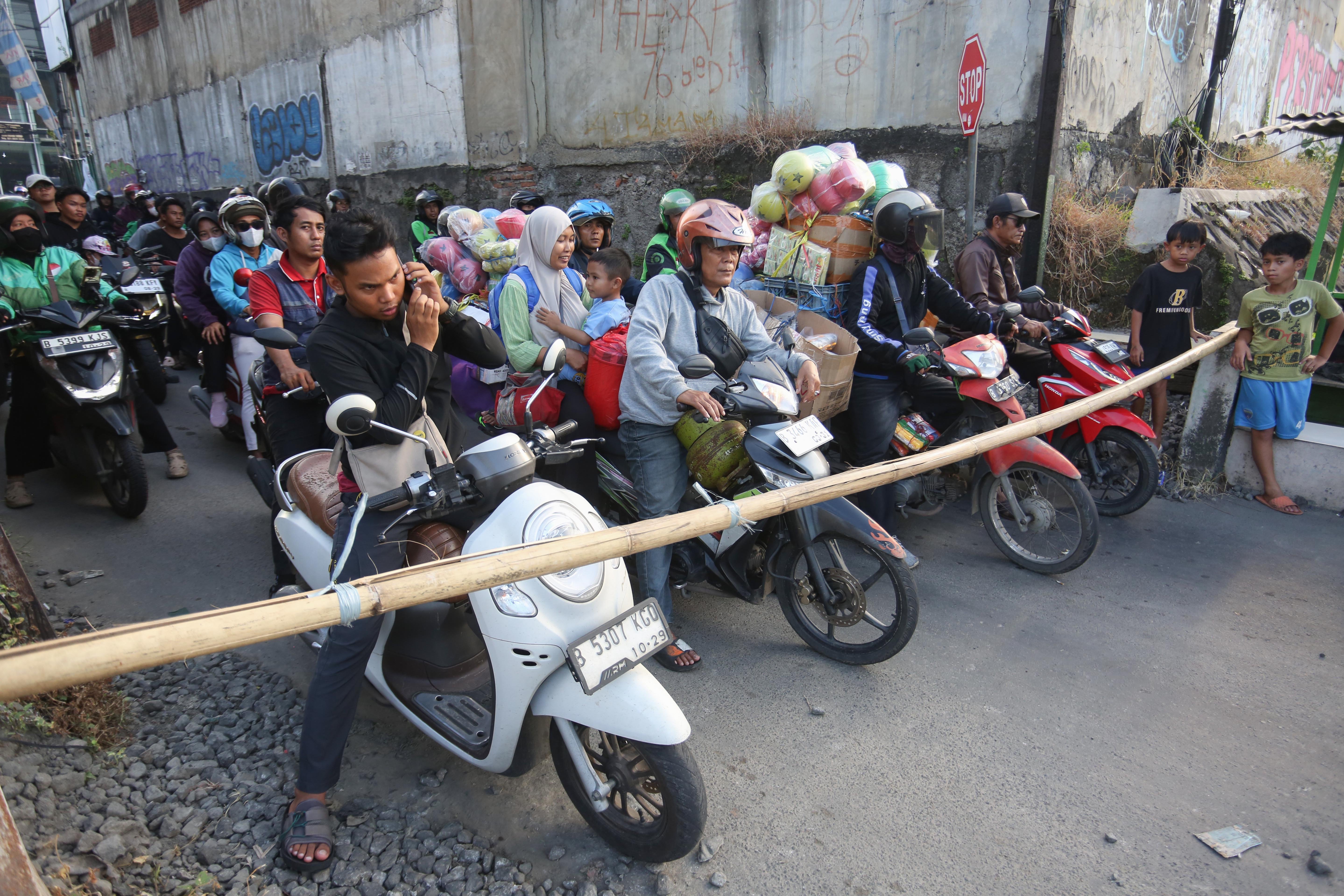 Pengendara menunggu kereta api melintas di perlintasan sebidang di Jalan Ampera, Kota Bekasi, Jawa Barat, Senin (27/4/2026). PT Kereta Api Indonesia (KAI) Persero menyatakan akan menutup berbagai jalur perlintasan kereta api sebidang yang tidak memenuhi syarat keselamatan menyusul dua tragedi yang melibatkan KRL Commuter Line dengan Taksi Green SM dan KA Argo Bromo Anggrek dengan KRL Commuter Line.