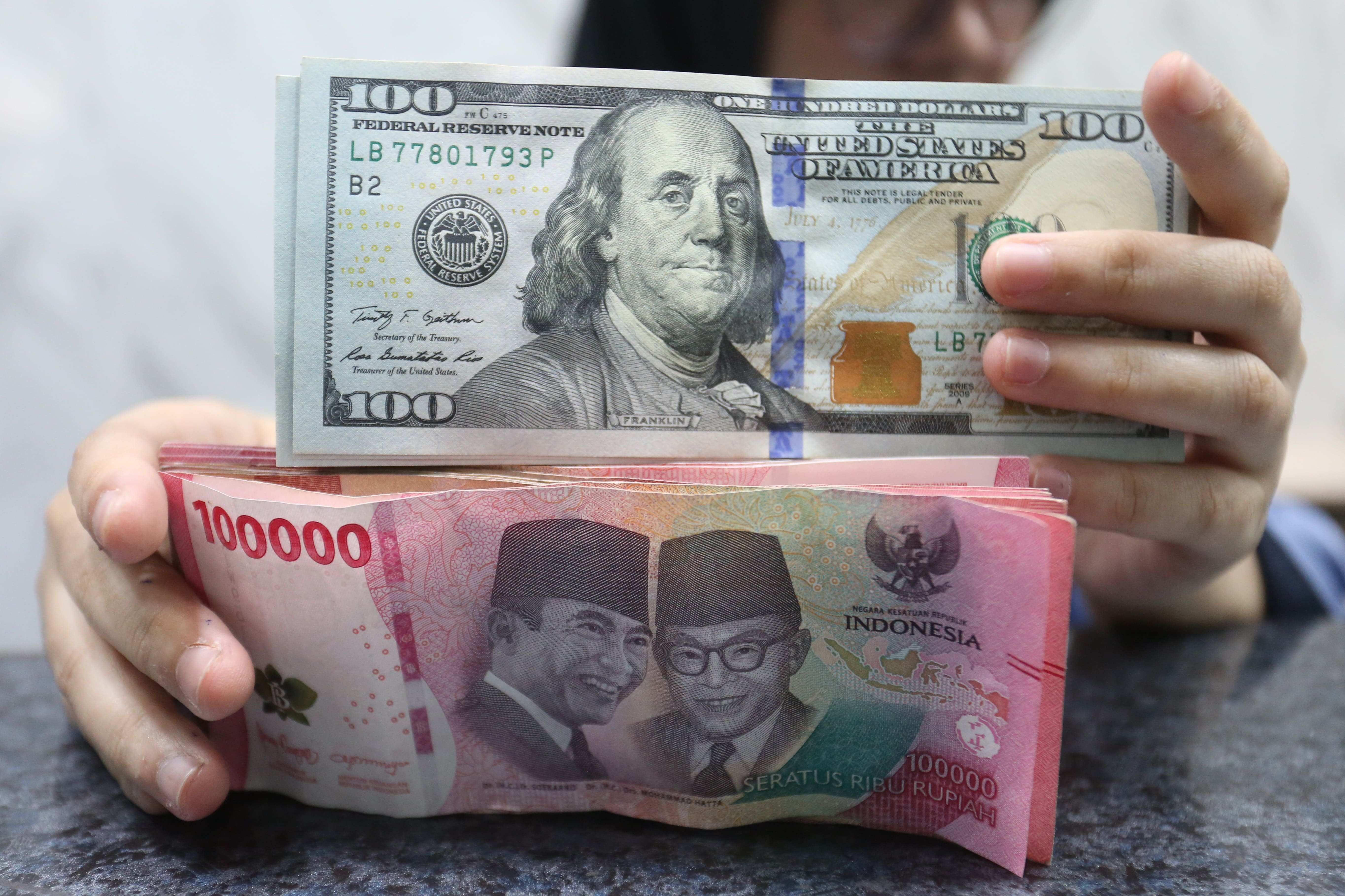 Petugas menunjukkan pecahan mata uang rupiah dan dolar Amerika Serikat (AS) di gerai penukaran uang asing di Jakarta, Rabu (18/5/2026). Nilai tukar rupiah rupiah terhadap dolar AS ditutup melemah Rp 17.668 pada perdagangan hari ini dari sebelumnya Rp 17.597 per dolar AS.