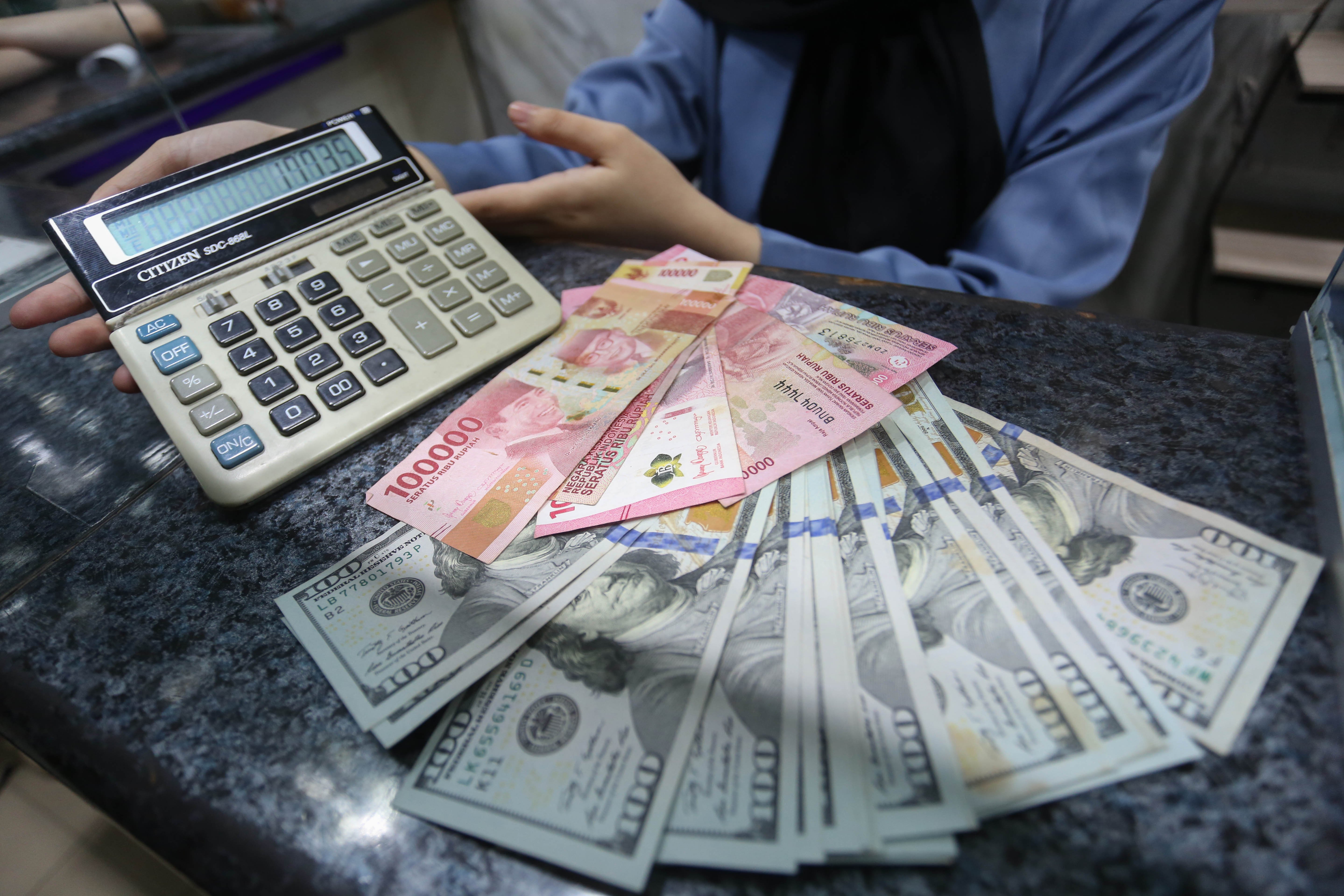 Petugas menghitung pecahan mata uang rupiah dan dolar Amerika Serikat (AS) di gerai penukaran uang asing di Jakarta, Rabu (18/5/2026). Nilai tukar rupiah rupiah terhadap dolar AS ditutup melemah Rp 17.668 pada perdagangan hari ini dari sebelumnya Rp 17.597 per dolar AS.