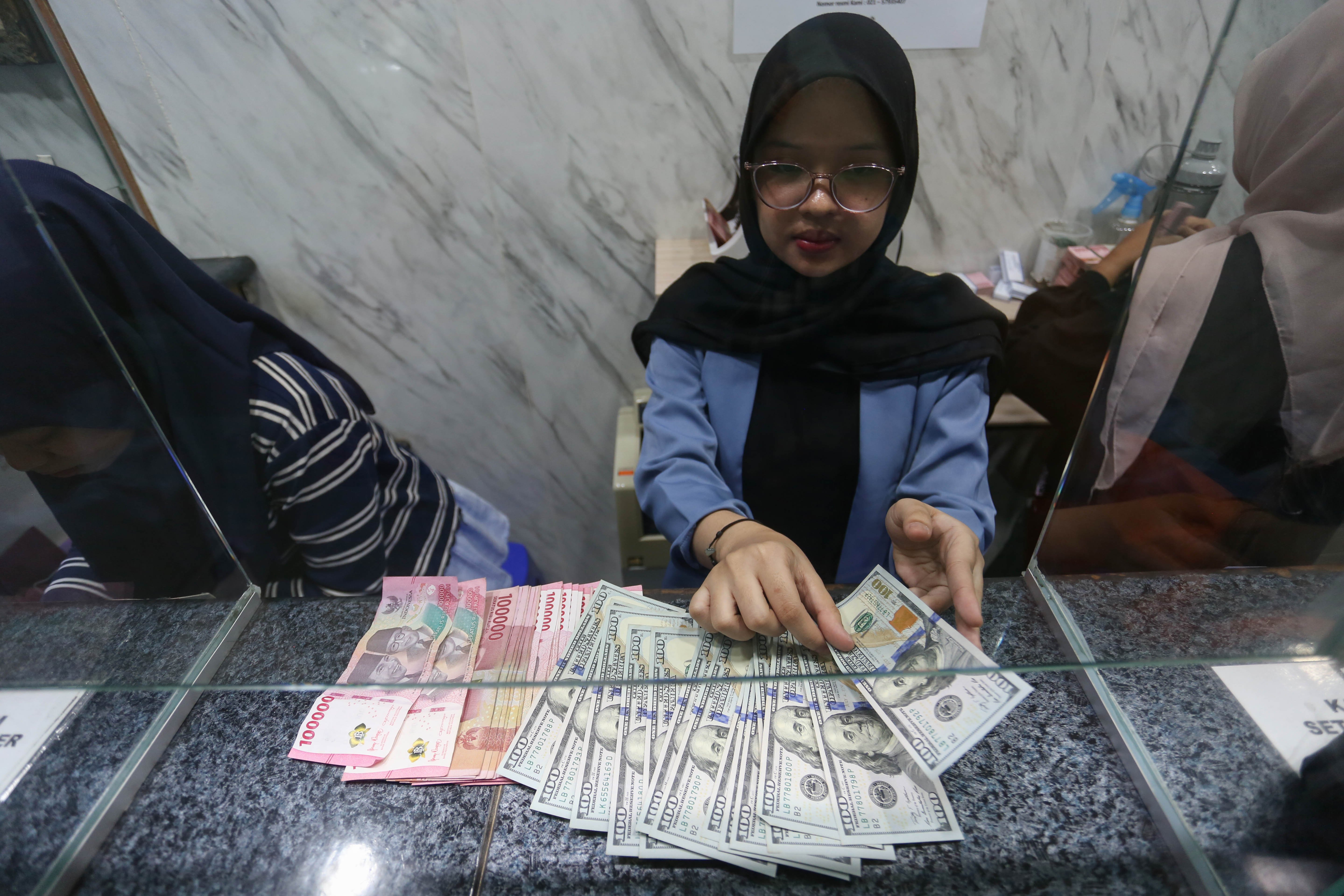 Petugas menghitung pecahan mata uang rupiah dan dolar Amerika Serikat (AS) di gerai penukaran uang asing di Jakarta, Rabu (18/5/2026). Nilai tukar rupiah rupiah terhadap dolar AS ditutup melemah Rp 17.668 pada perdagangan hari ini dari sebelumnya Rp 17.597 per dolar AS.