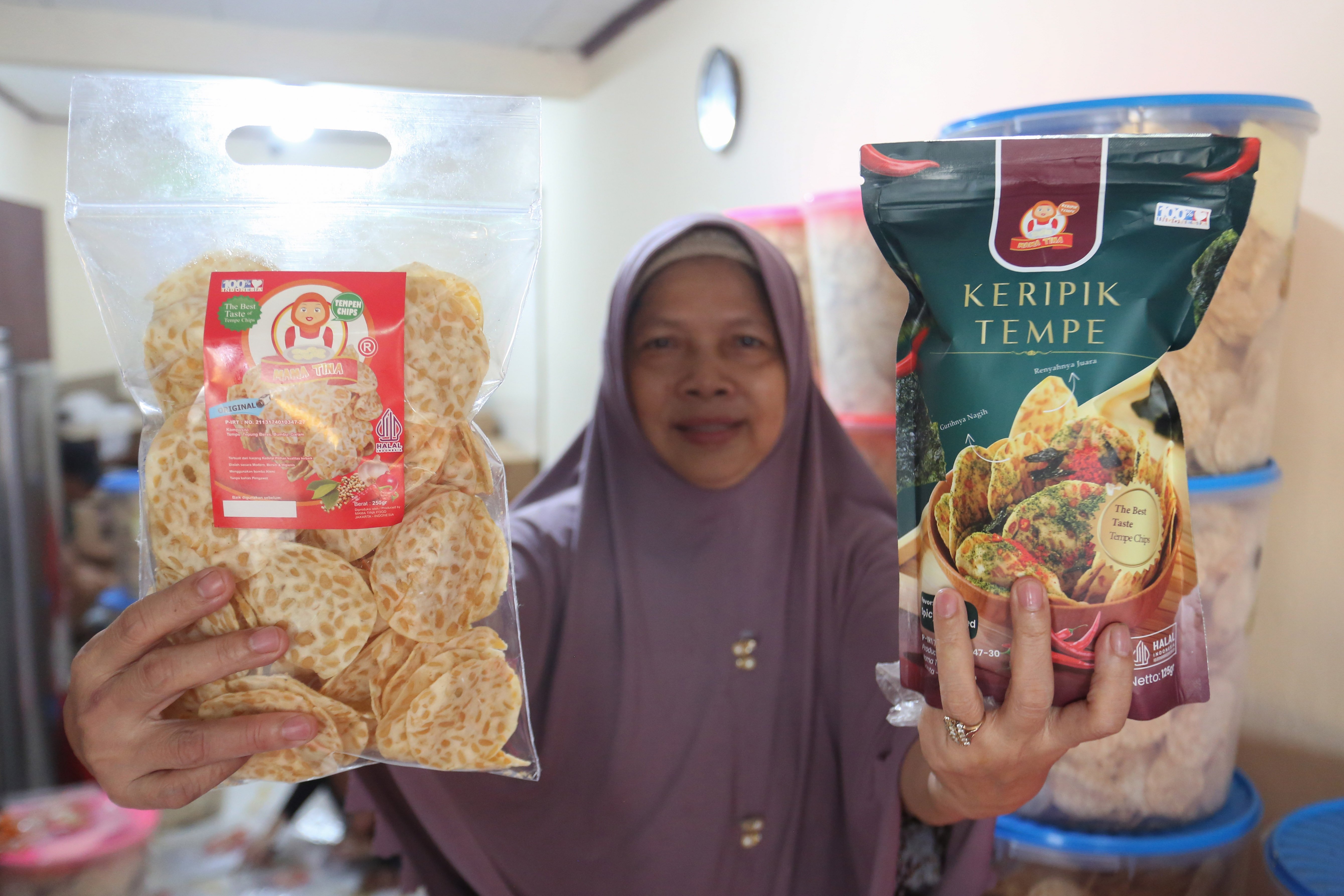 Martinah menunjukkan keripik tempe yang sudah dikemas di usaha rumahan di kawasan Kramat Pela, Kebayoran Baru, Jakarta Selatan, Selasa (19/5/2026). Martinah (61) selaku pemilik usaha ini mengungkapkan harga bahan baku kedelai yang melonjak akibat melemahnya nilai tukar rupiah membuat harga produk keripik tempe di tempatnya ikut naik Rp 5.000 dari sebelumnya Rp 75 ribu per kilogram (kg) menjadi Rp 80 ribu per kg.