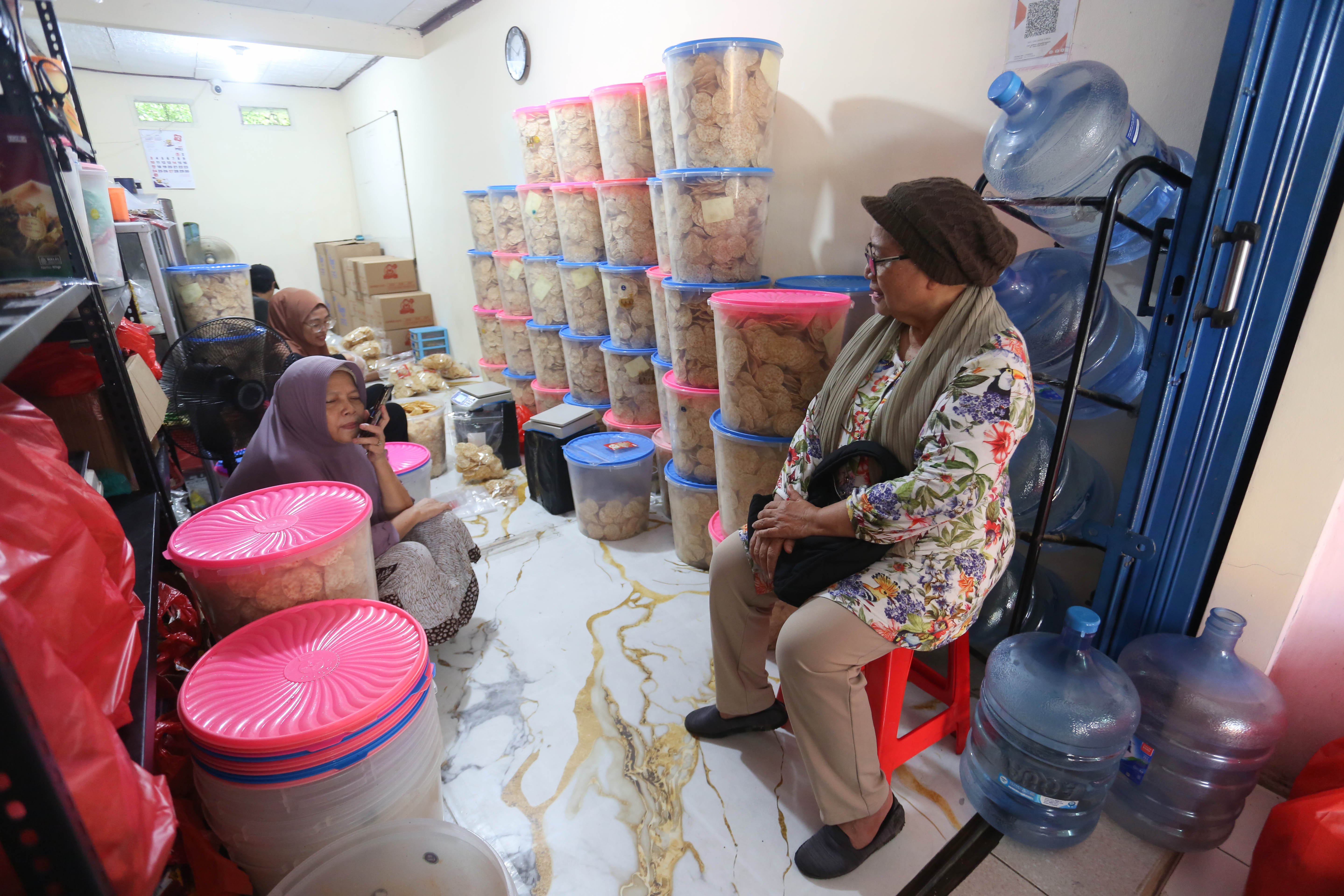 Pembeli (kanan) melihat pembuatan keripik tempe di usaha rumahan di kawasan Kramat Pela, Kebayoran Baru, Jakarta Selatan, Selasa (19/5/2026). Martinah (61) selaku pemilik usaha ini mengungkapkan harga bahan baku kedelai yang melonjak akibat melemahnya nilai tukar rupiah membuat harga produk keripik tempe di tempatnya ikut naik Rp 5.000 dari sebelumnya Rp 75 ribu per kilogram (kg) menjadi Rp 80 ribu per kg.