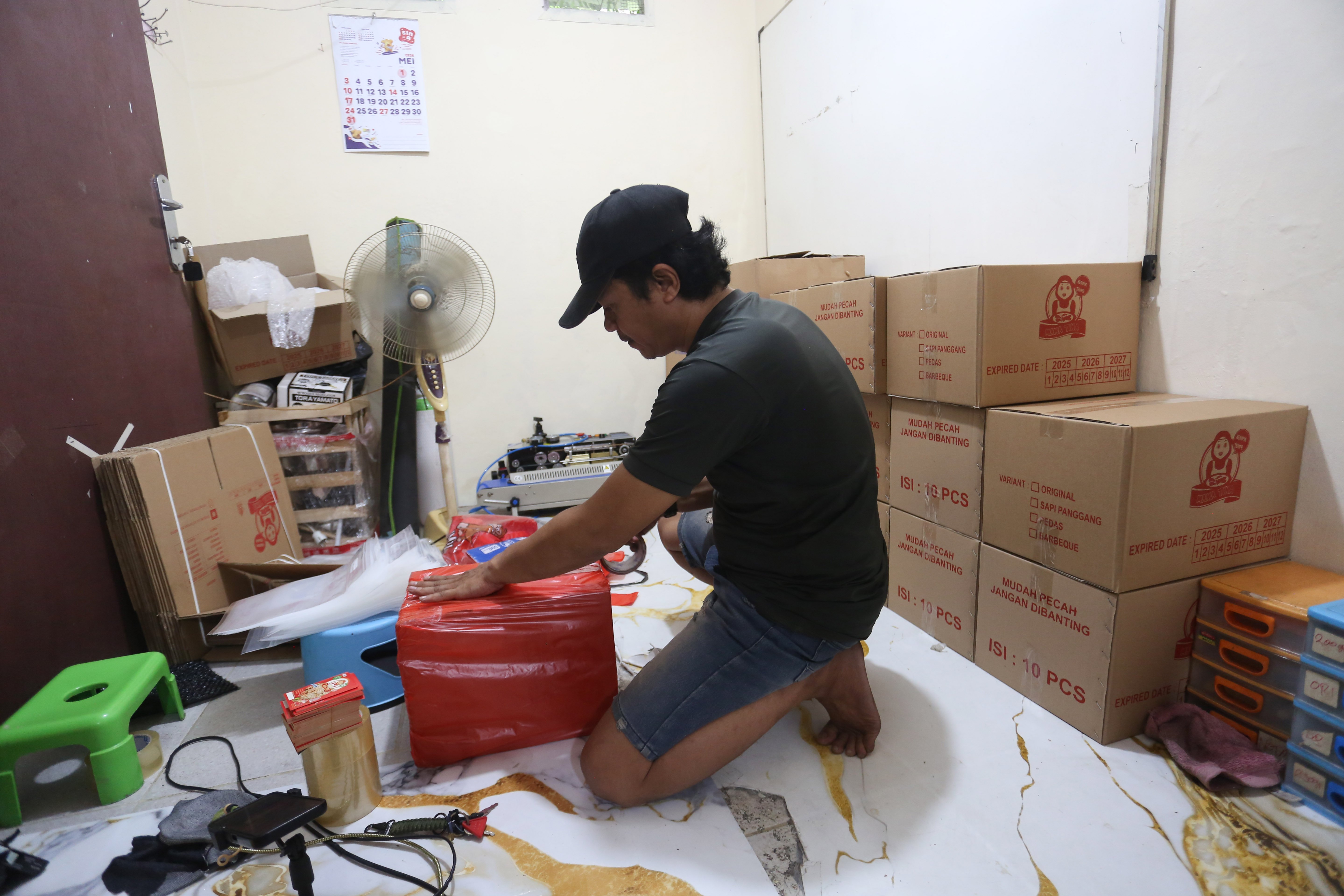 Pekerja mengemas keripik tempe untuk dikirimkan ke pelanggan di usaha rumahan di kawasan Kramat Pela, Kebayoran Baru, Jakarta Selatan, Selasa (19/5/2026). Martinah (61) selaku pemilik usaha ini mengungkapkan harga bahan baku kedelai yang melonjak akibat melemahnya nilai tukar rupiah membuat harga produk keripik tempe di tempatnya ikut naik Rp 5.000 dari sebelumnya Rp 75 ribu per kilogram (kg) menjadi Rp 80 ribu per kg. 