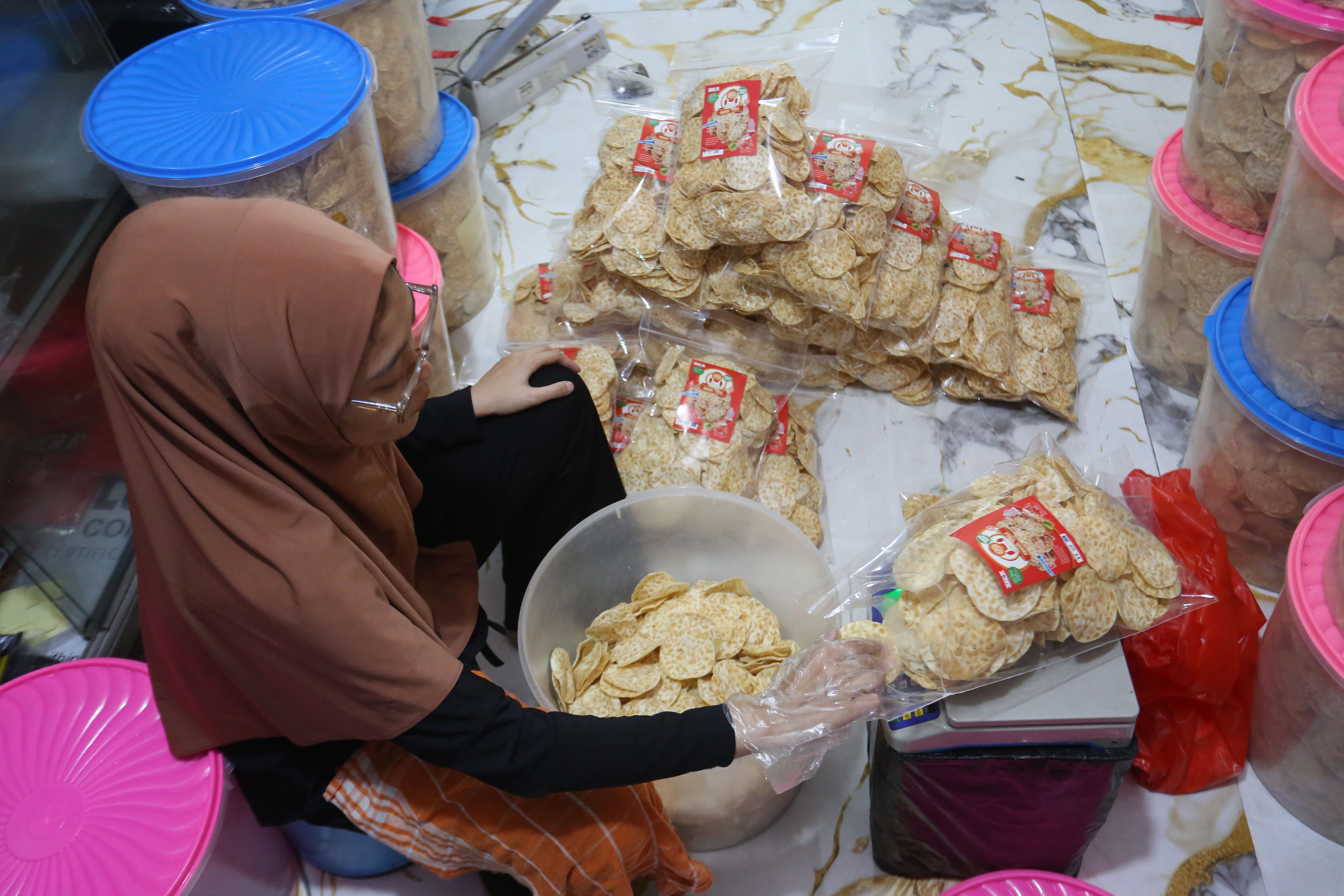 Pekerja mengemas keripik tempe di usaha rumahan di kawasan Kramat Pela, Kebayoran Baru, Jakarta Selatan, Selasa (19/5/2026). Martinah (61) selaku pemilik usaha ini mengungkapkan harga bahan baku kedelai yang melonjak akibat melemahnya nilai tukar rupiah membuat harga produk keripik tempe di tempatnya ikut naik Rp 5.000 dari sebelumnya Rp 75 ribu per kilogram (kg) menjadi Rp 80 ribu per kg. 