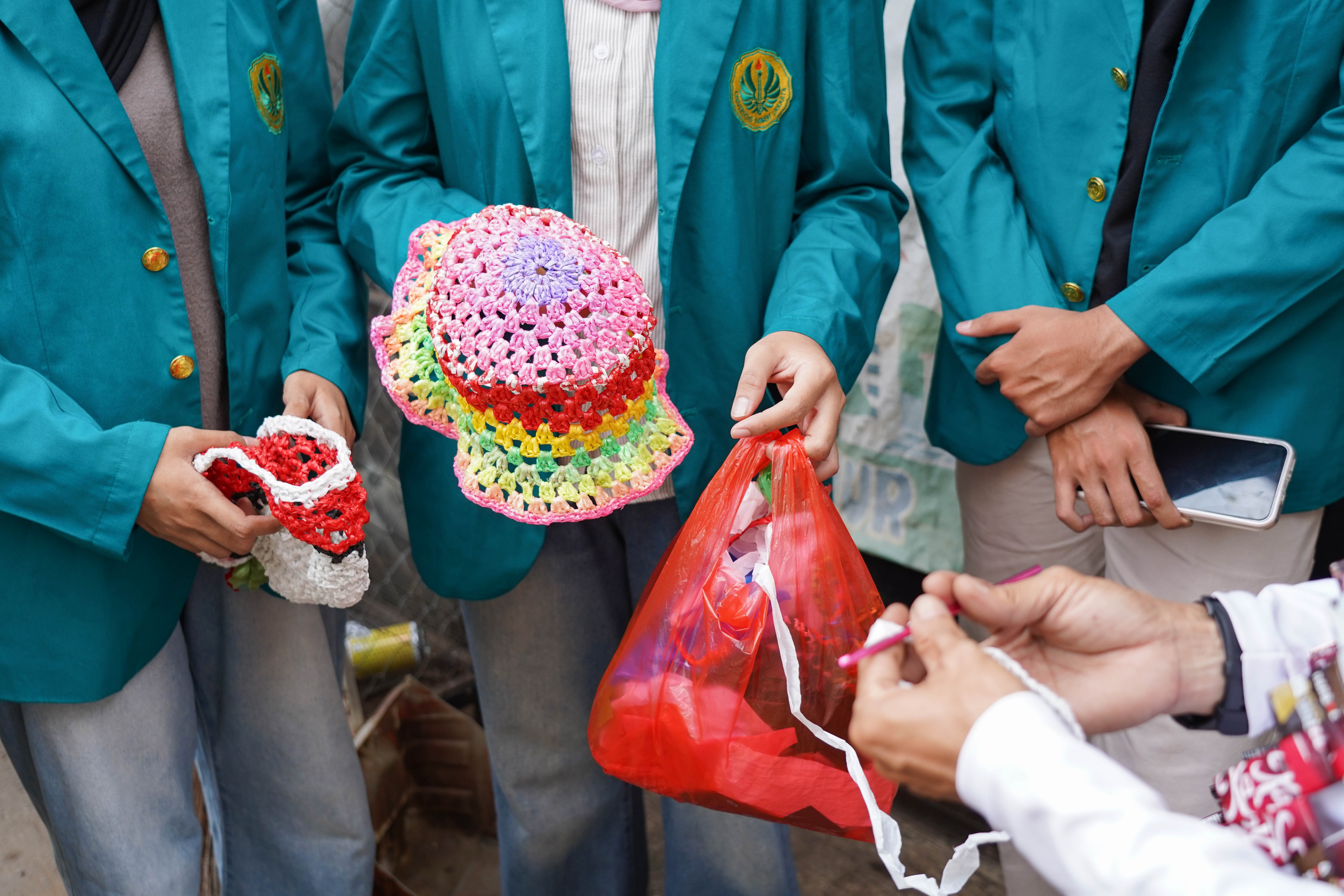Pengurus Bank Sampah Persatuan, Rahmat (kanan) menyampaikan edukasi kepada mahasiswa mengenai pembuatan topi dari sampah plastik di kawasan RT.003/RW.008, Duren Sawit, Jakarta Timur, Jumat (22/5/2026). Kegiatan tersebut dilakukan guna mengajak masyarakat untuk memilah dan mengolah sampah dari rumah.