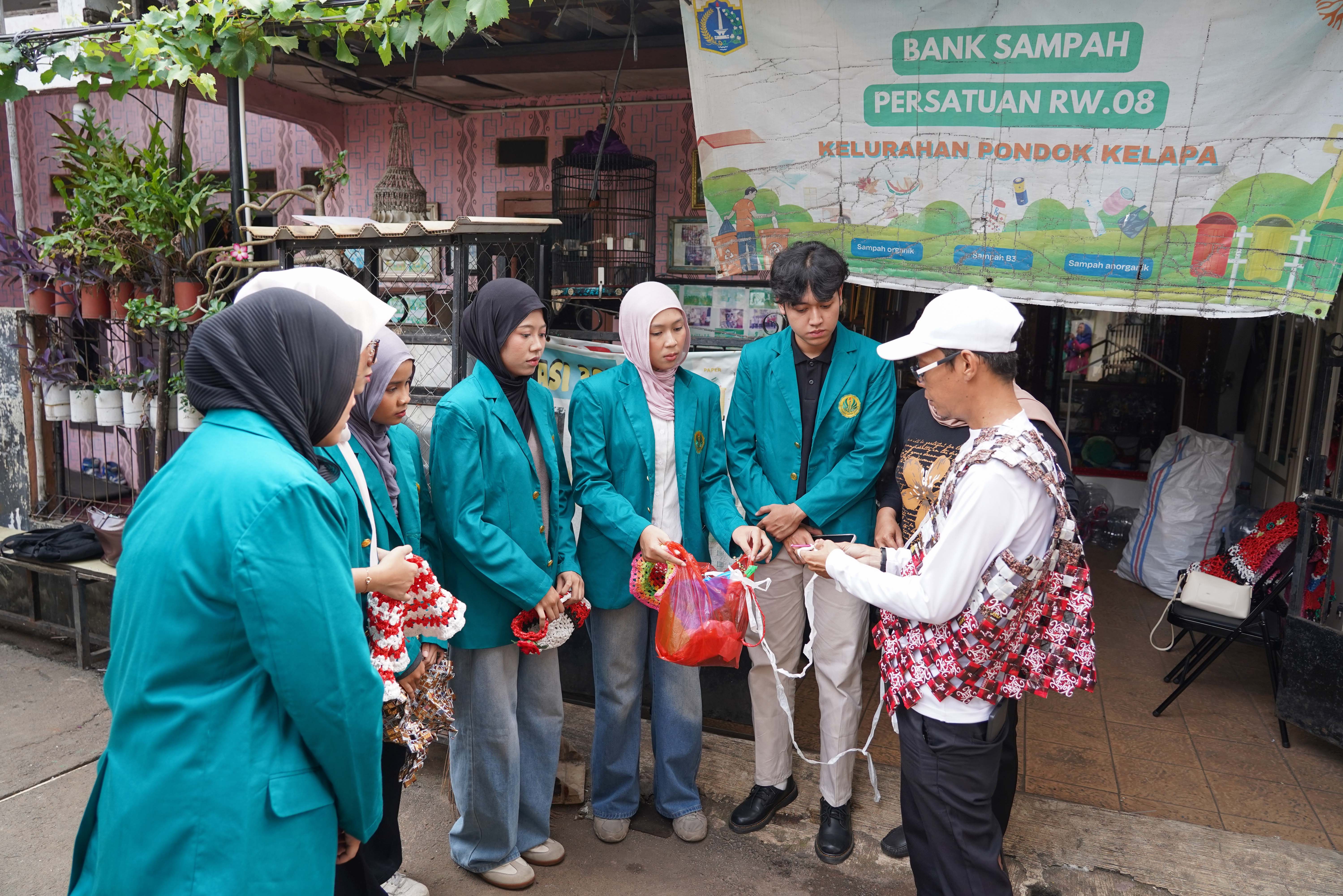 Pengurus Bank Sampah Persatuan, Rahmat (kanan) menyampaikan edukasi kepada mahasiswa mengenai pembuatan topi dari sampah plastik di kawasan RT.003/RW.008, Duren Sawit, Jakarta Timur, Jumat (22/5/2026). Kegiatan tersebut dilakukan guna mengajak masyarakat untuk memilah dan mengolah sampah dari rumah.