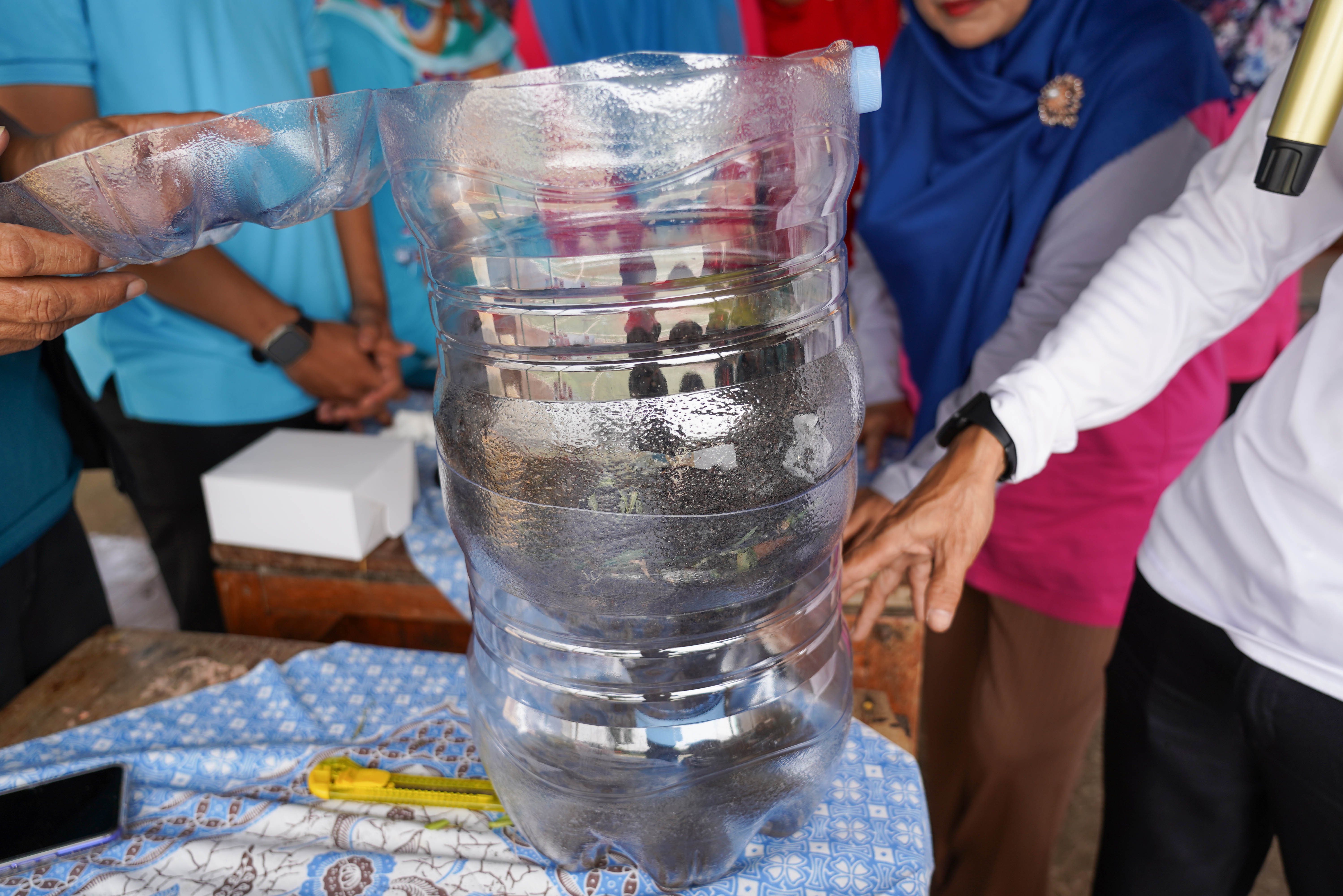 Pengurus Bank Sampah Persatuan, Rahmat (kanan) menyampaikan edukasi pembuatan wadah komposter skala rumahan di Taman Akur Warga, Duren Sawit, Jakarta Timur, Jumat (22/5/2026). Kegiatan tersebut dilakukan guna mengajak masyarakat untuk memilah dan mengolah sampah dari rumah.