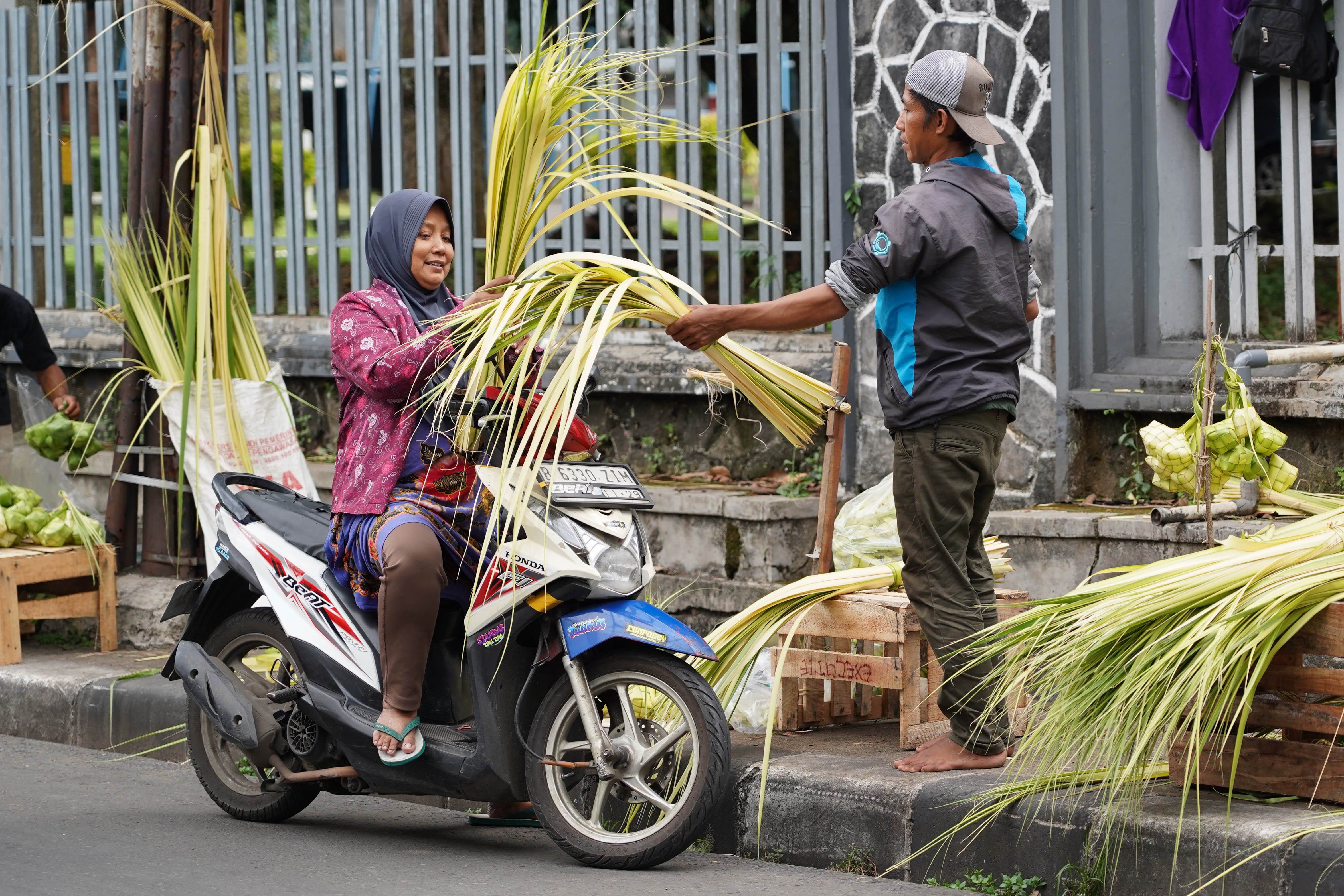 Pedagang melayani calon pembeli yang hendak membeli ketupat di Pasar Pondok Labu, Jakarta Selatan, Senin (25/5/2026). Ketupat tersebut dijual Rp 10 ribu per ikatnya atau Rp 1.000 per ketupat dan untuk daunnya saja yang belum dianyam dihargai Rp 500 per helai.