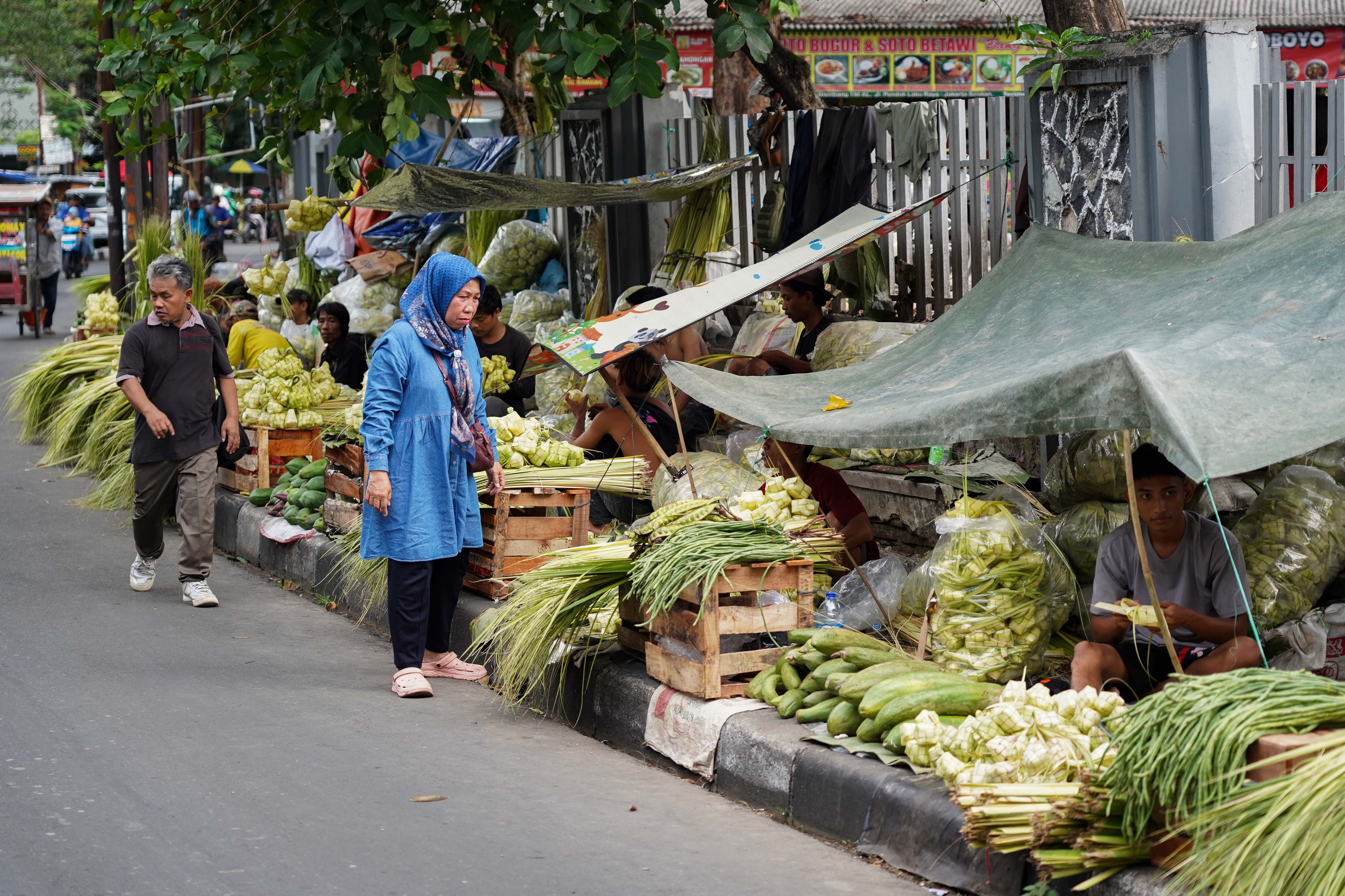 Calon pembeli melihat ketupat yang dijajakan di Pasar Pondok Labu, Jakarta Selatan, Senin (25/5/2026). Ketupat tersebut dijual Rp 10 ribu per ikatnya atau Rp 1.000 per ketupat dan untuk daunnya saja yang belum dianyam dihargai Rp 500 per helai.