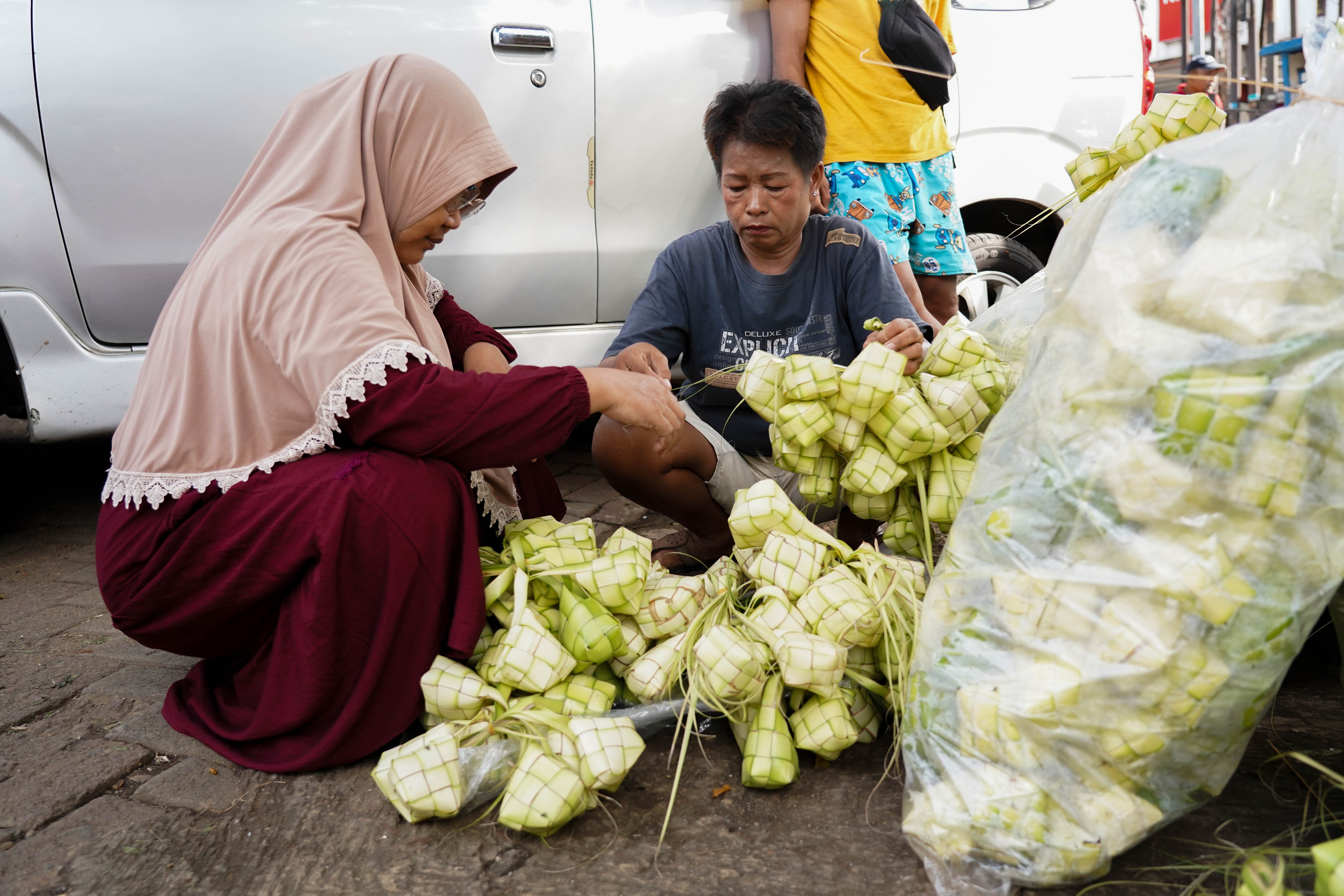 Pedagang melayani calon pembeli yang hendak membeli ketupat di Pasar Pondok Labu, Jakarta Selatan, Senin (25/5/2026). Ketupat tersebut dijual Rp 10 ribu per ikatnya atau Rp 1.000 per ketupat dan untuk daunnya saja yang belum dianyam dihargai Rp 500 per helai.