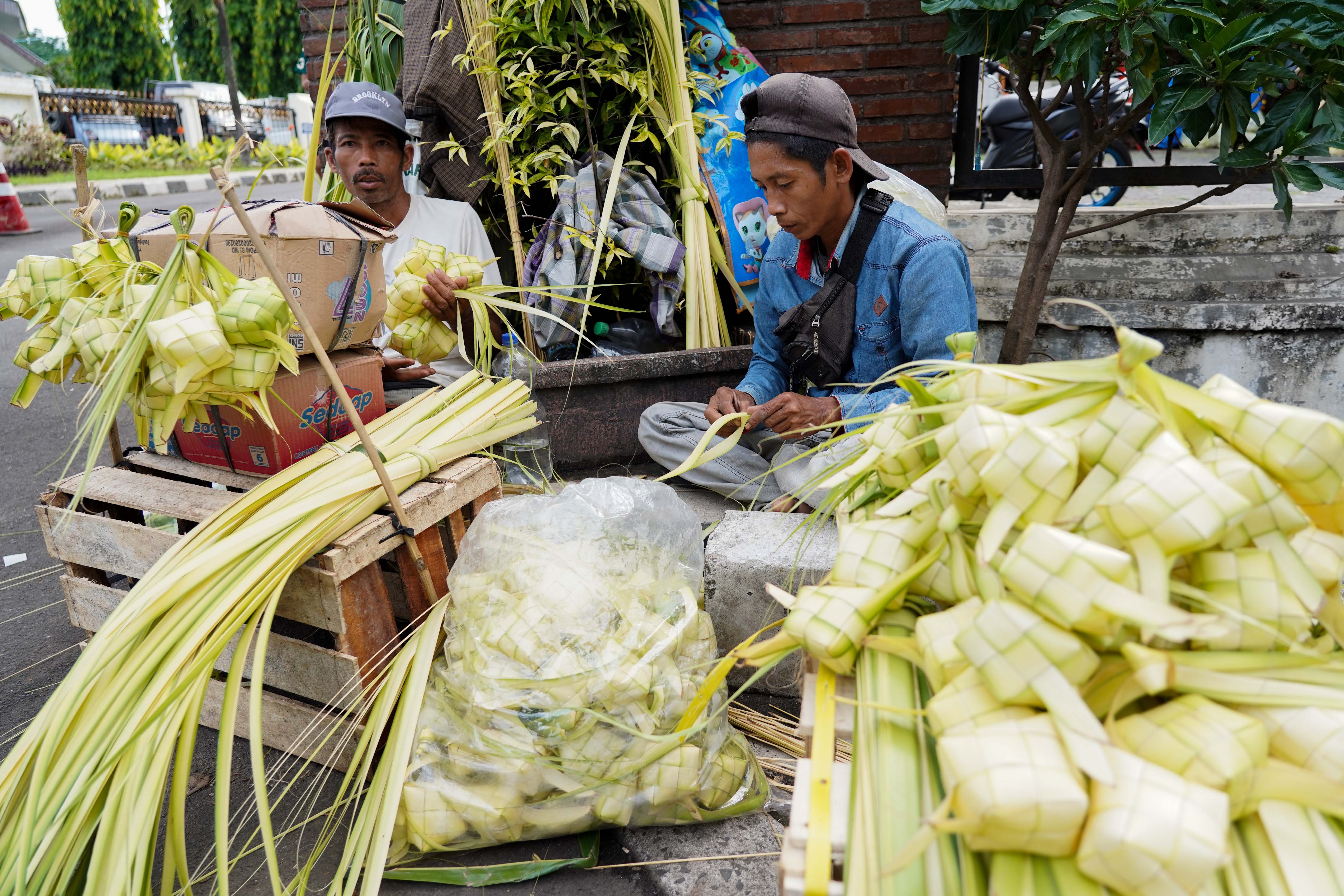 Pedagang menganyam ketupat yang dijualnya di Pasar Pondok Labu, Jakarta Selatan, Senin (25/5/2026). Ketupat tersebut dijual Rp 10 ribu per ikatnya atau Rp 1.000 per ketupat dan untuk daunnya saja yang belum dianyam dihargai Rp 500 per helai.