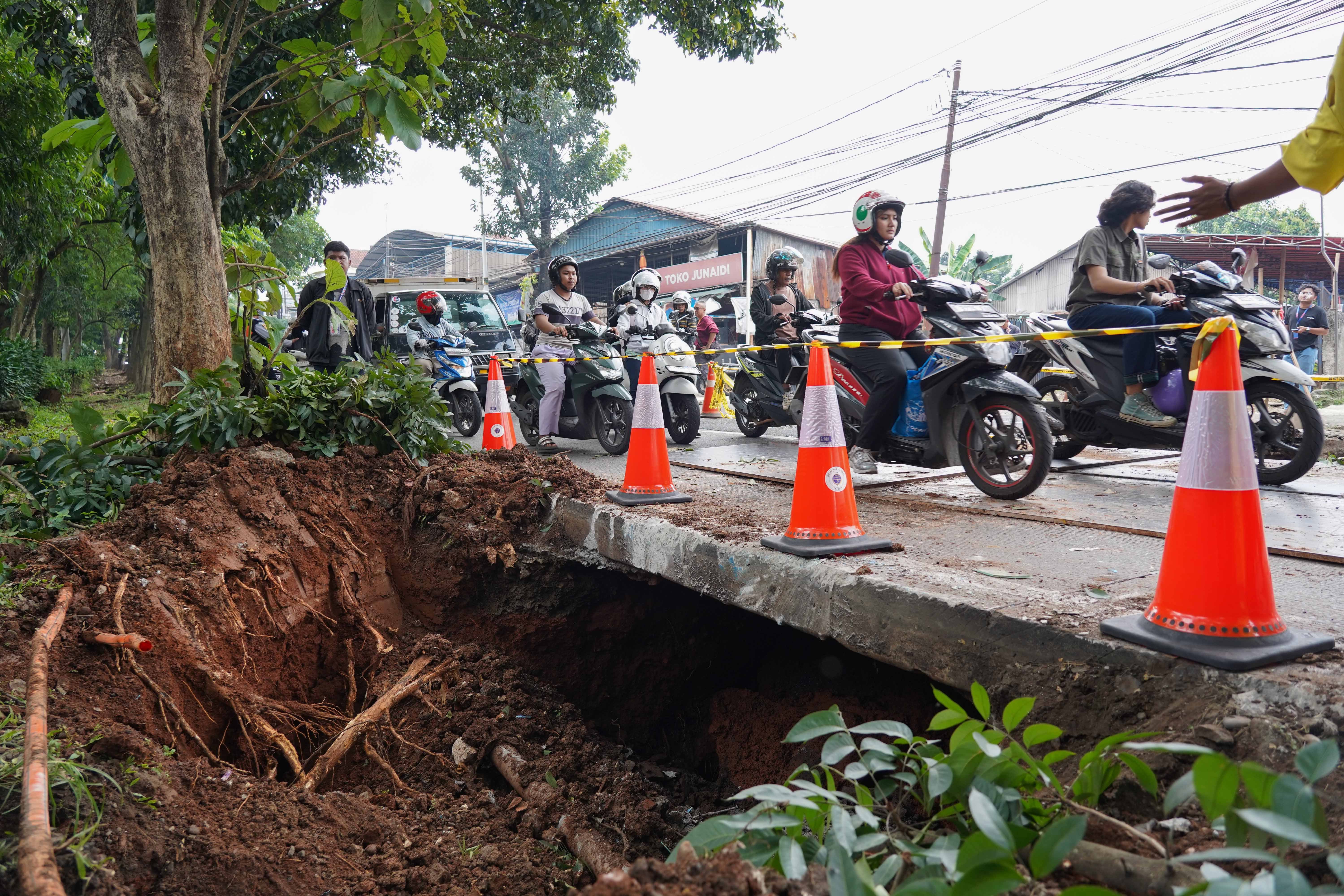 Pengendara sepeda motor melintas di dekat lubang dari amblasnya Jalan Raya Lenteng Agung, Jagakarsa, Jakarta Selatan, Jumat (29/5/2026). Akibat jalan tersebut amblas sedalam tiga meter dengan lebar empat meter ini membuat arus lalu lintas dari arah Jakarta menuju Depok mengalami kemacetan.